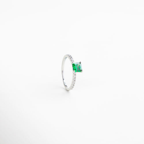 Close-up del Anillo Nisii Green mostrando la piedra central verde y las zirconias que la rodean. Detalle cercano de la textura plateada del anillo y el brillo de las zirconias. Zoom a la piedra esmeralda central con incrustaciones brillantes, resaltando su color y diseño sofisticado. Primer plano del anillo plateado con zirconias y piedra verde, acabado pulido y elegante. Detalle de la circunferencia de zirconias alrededor de la piedra verde central, diseño refinado y lujoso