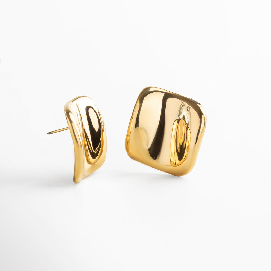 Detalle de textura abstracta en aretes cuadrados dorados, Primer plano de pendientes dorados con superficie artística, Close-up de acabado texturizado en pendientes geométricos, Acabado dorado brillante y texturizado en aretes cuadrados