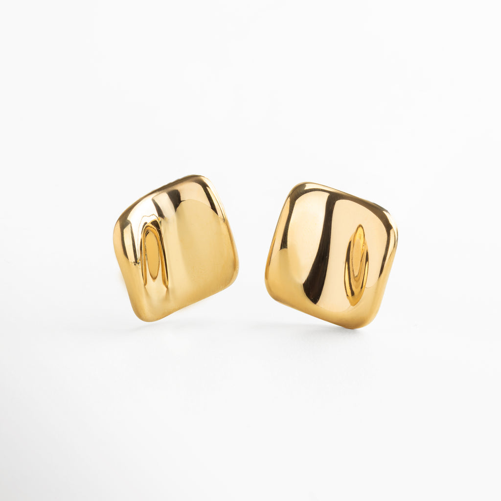Aretes dorados cuadrados con textura abstracta y diseño moderno, Pendientes cuadrados en chapa de oro 18K con acabado artístico, Aretes geométricos dorados con estilo escultórico y sofisticado, Pendientes dorados con forma cuadrada y diseño contemporáneo