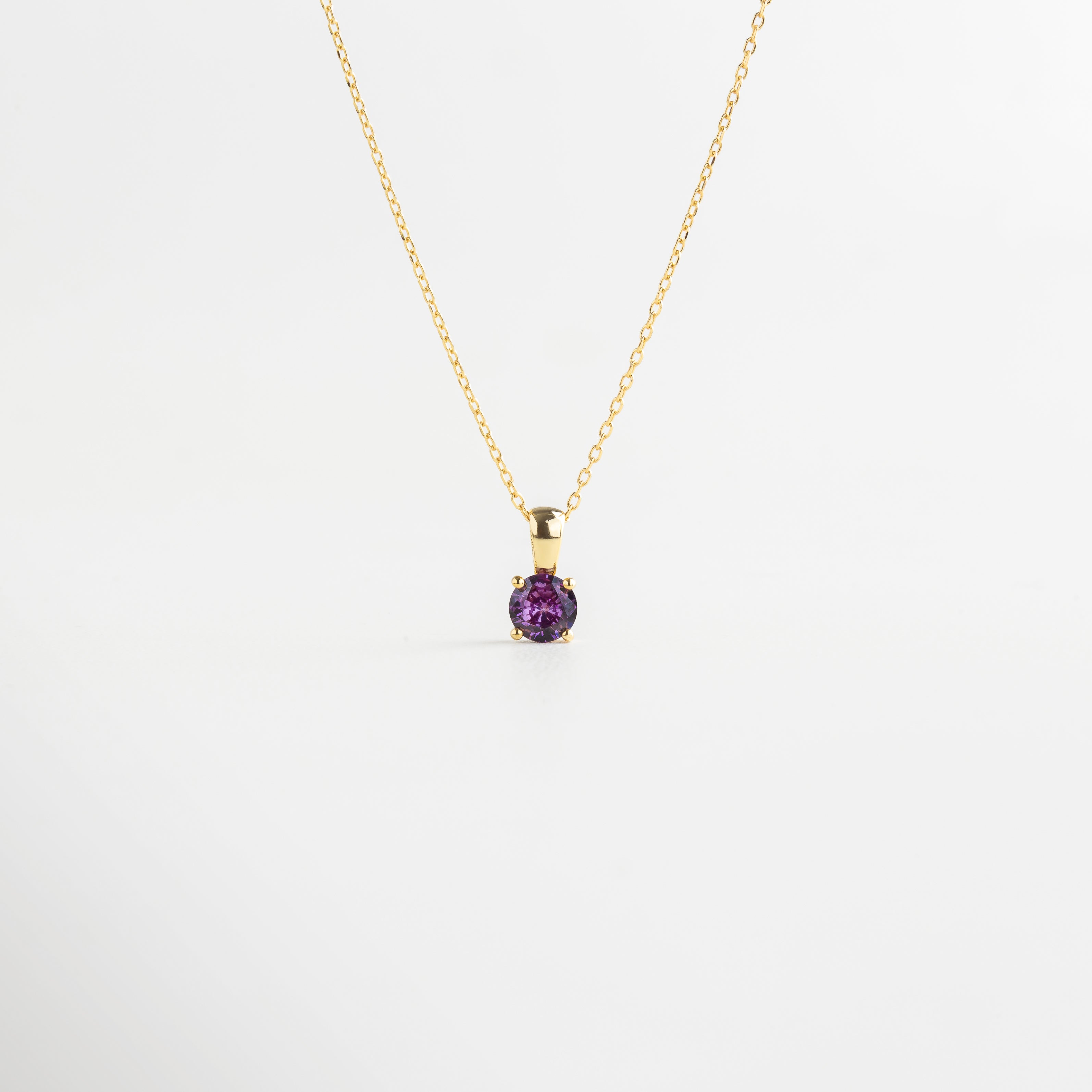 Vista superior del Collar del Mes extendido, mostrando su longitud de 22 cm y piedra central de color. Collar dorado con piedra pequeña de color visto desde arriba, resaltando su delicadeza y diseño sutil.
Toma cenital del collar elaborado en plata 925 con acabado dorado y zirconia central de 0.5 mm.
Collar del Mes extendido en plano superior, con cada versión luciendo una piedra distinta y colorida. Perspectiva desde arriba del Collar del Mes, con detalle central brillante y cadena dorada l