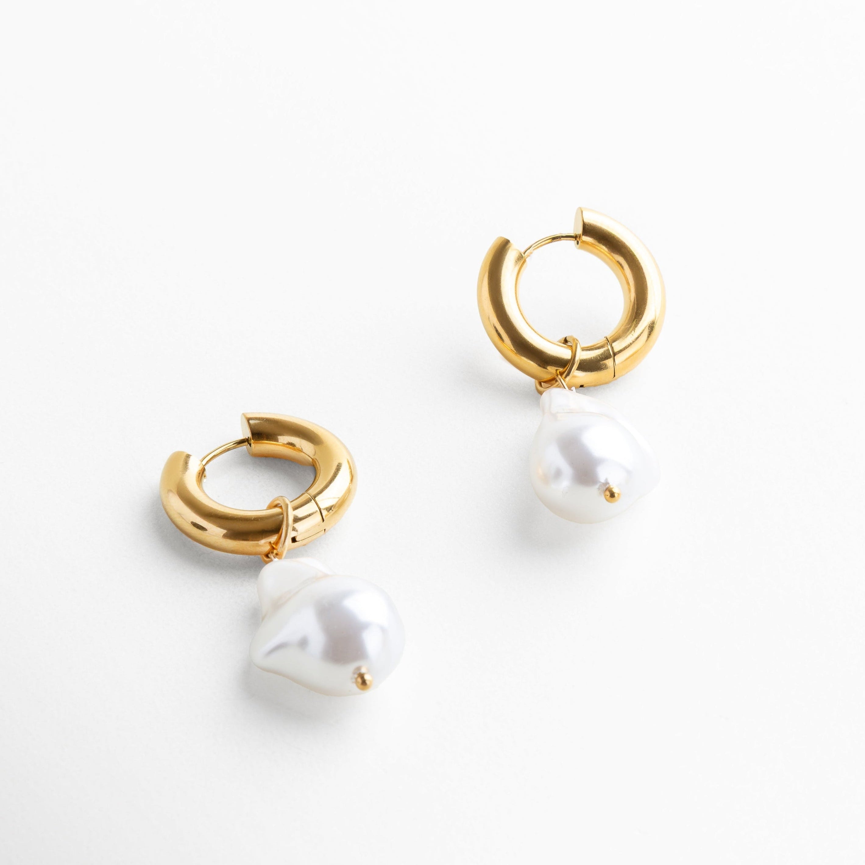 Aretes Venus Hoops con perla en vista lateral, Perfil de arete dorado con perla desmontable, Hoops doradas con caída de perla vista en ángulo, Diseño convertible de aretes con perla en dorado