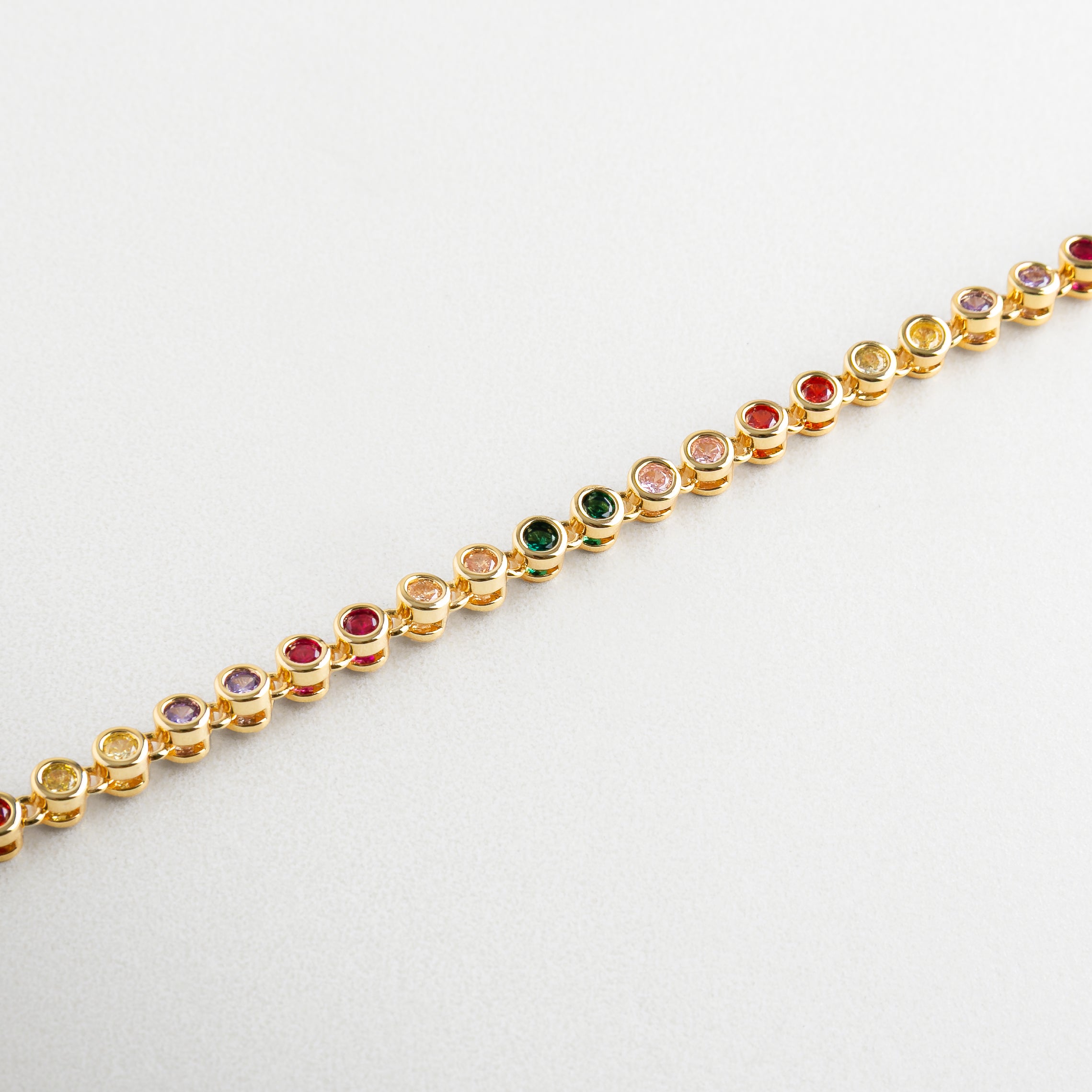 Pulsera Rodas Colores vista en ángulo con destellos vivos, Diseño en dorado con zirconias de diferentes colores, Pulsera estilizada con textura multicolor y dorado, Acentos vibrantes en pulsera con estructura delicada
