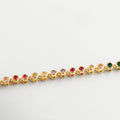 Detalle de zirconias cúbicas de colores en pulsera dorada, Primer plano de piedras multicolor sobre chapa de oro, Incrustaciones coloridas en pulsera con acabado brillante, Zirconias facetadas en gama multicolor sobre oro