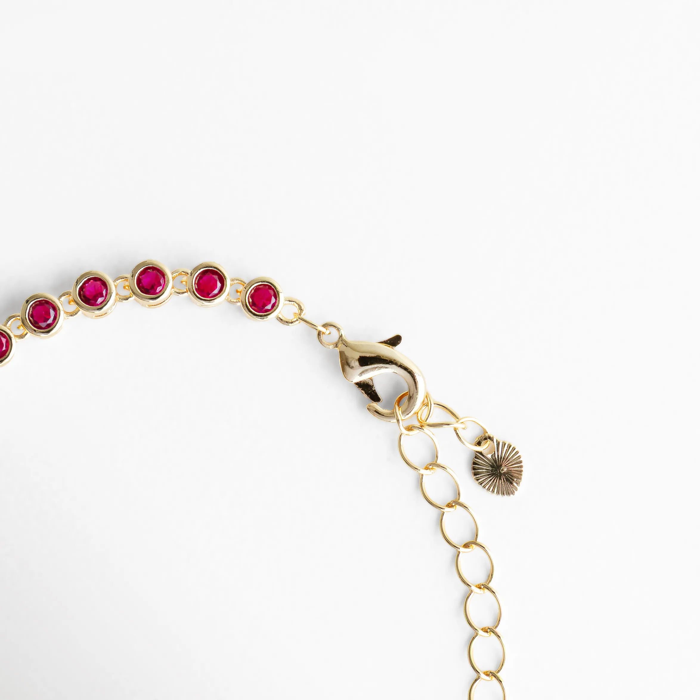 Cadena ajustable de pulsera dorada con zirconias fucsia, Detalle del broche y extensión de pulsera con diseño fino, Cierre de pulsera con acabado en oro 18K y piedras fucsia, Vista del sistema ajustable de pulsera con cadena dorada, Detalle del extremo de pulsera con zirconias fucsia y broche