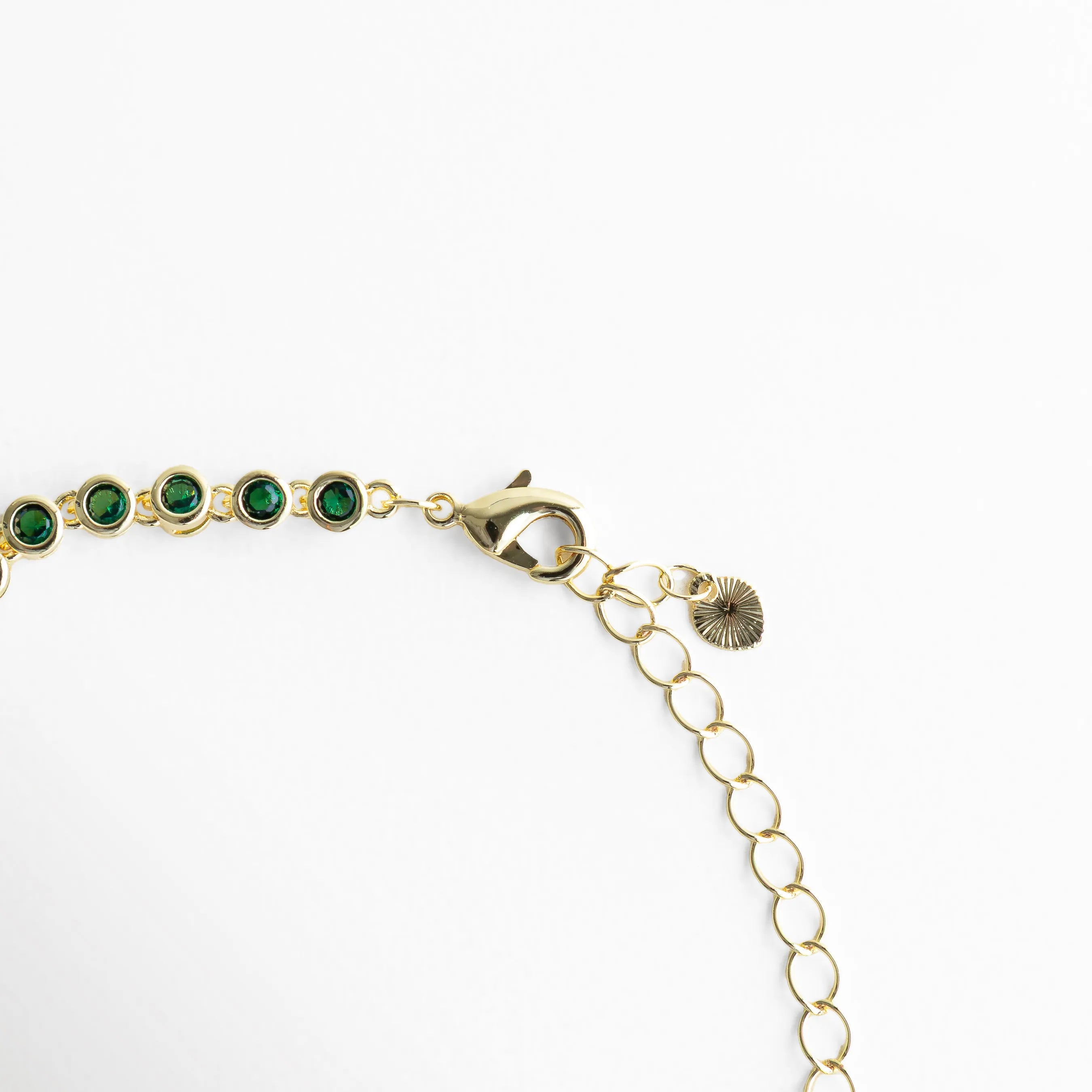 Cadena ajustable de pulsera dorada con zirconias verdes y cierre delicado, Detalle del broche y extensión de pulsera con diseño fino y elegante, Vista de la estructura de pulsera con eslabones dorados y piedras verdes, Pulsera ajustable con cadena dorada y zirconias verdes distribuidas, Segmento de pulsera con patrón continuo de piedras verdes brillantes