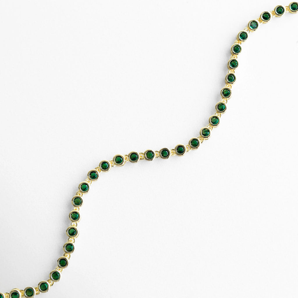 Pulsera dorada con zirconias verdes en forma curva y diseño elegante, Vista curva de pulsera con piedras verdes brillantes y acabado en oro 18K, Pulsera Rodas verde en ángulo curvo con diseño fluido y delicado, Curvatura de pulsera dorada con zirconias verdes y brillo sofisticado, Pulsera con forma ondulada y piedras verdes en acabado dorado