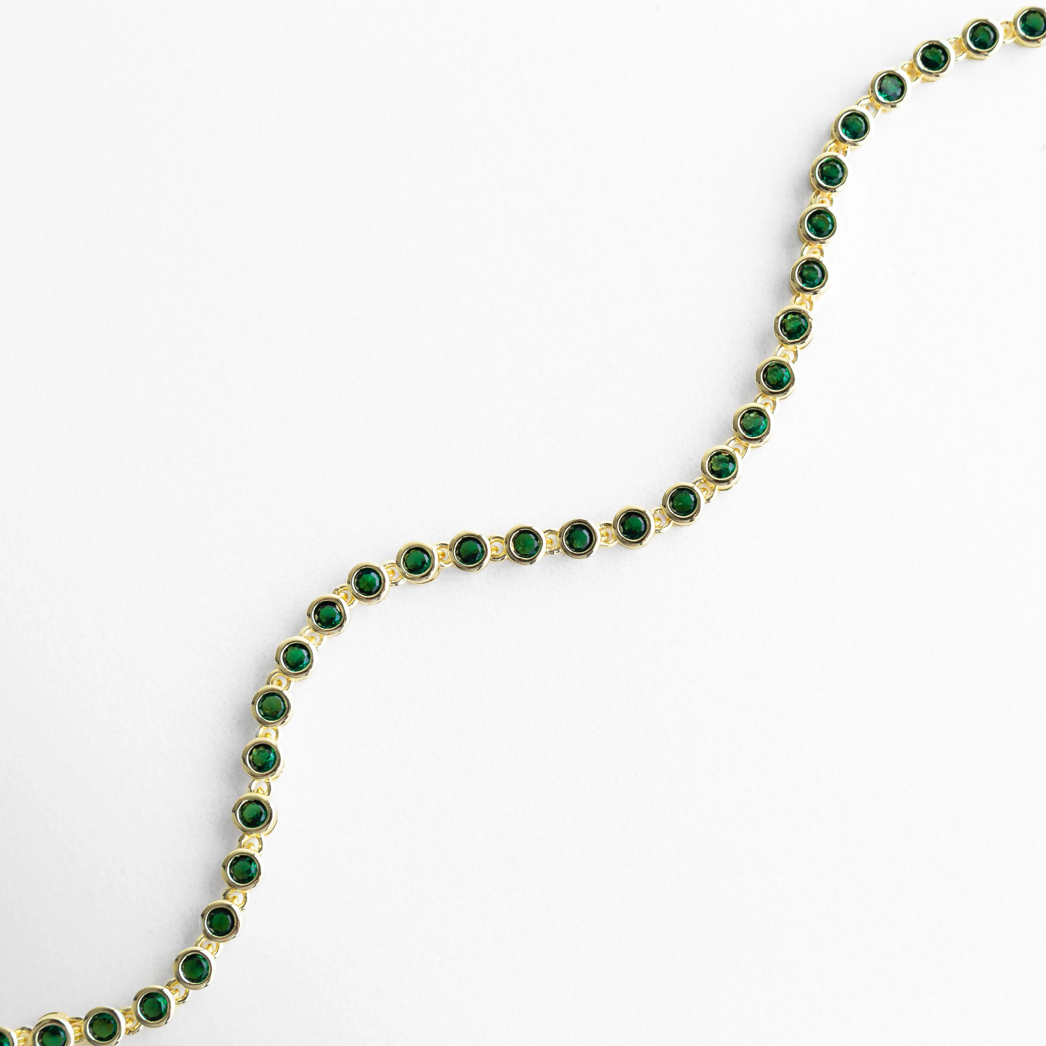 Pulsera dorada con zirconias verdes en forma curva y diseño elegante, Vista curva de pulsera con piedras verdes brillantes y acabado en oro 18K, Pulsera Rodas verde en ángulo curvo con diseño fluido y delicado, Curvatura de pulsera dorada con zirconias verdes y brillo sofisticado, Pulsera con forma ondulada y piedras verdes en acabado dorado