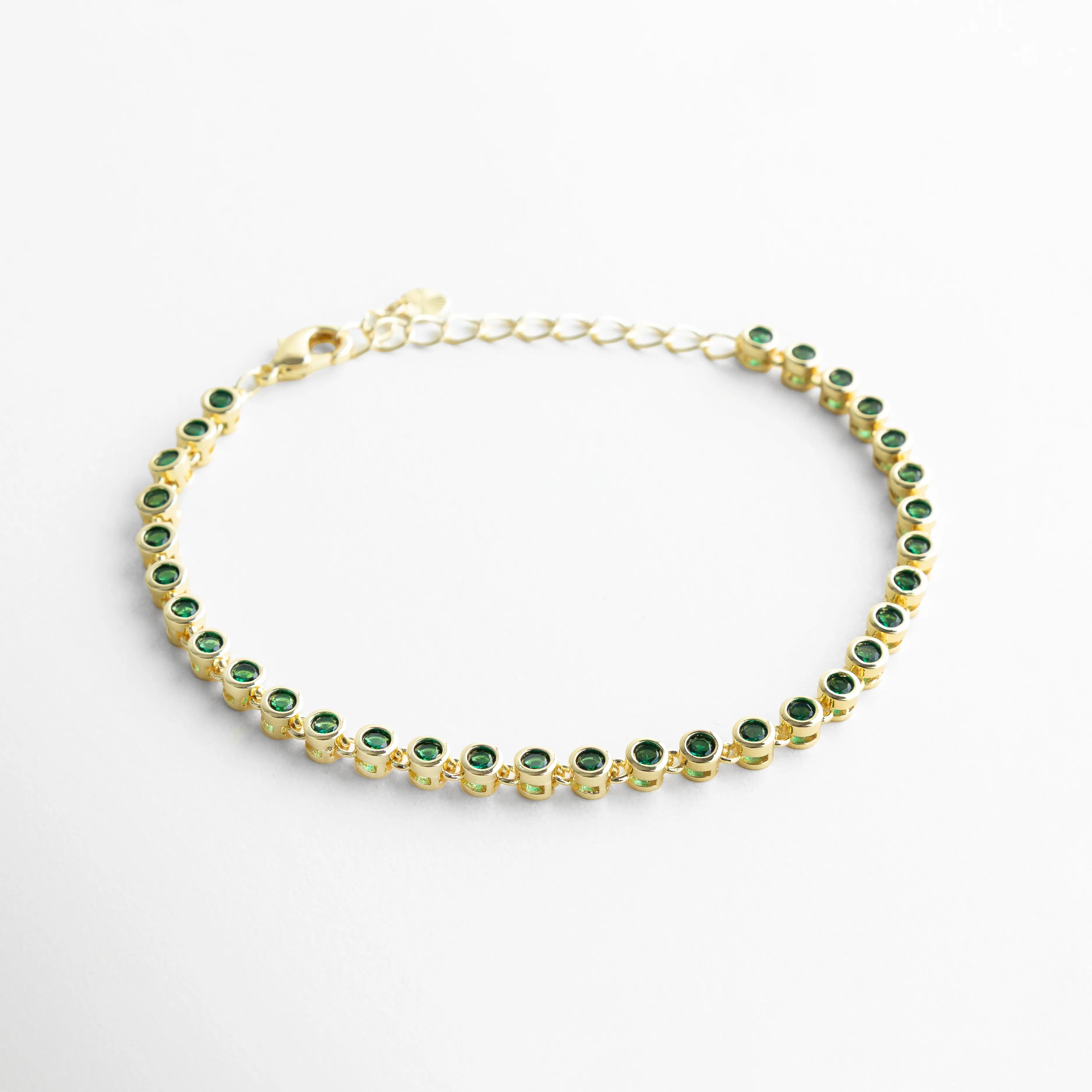 Vista lateral de pulsera dorada con zirconias verdes en patrón continuo, Perfil de pulsera con piedras verdes brillantes y diseño fino, Pulsera vista de lado con estructura delicada y zirconias verdes, Lateral de pulsera dorada con incrustaciones verdes y acabado elegante, Detalle lateral de pulsera con alineación de zirconias verdes
