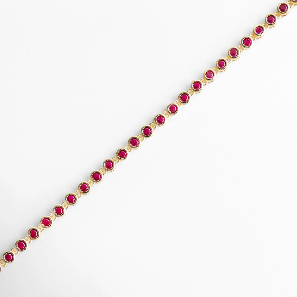 Vista lateral de pulsera dorada con zirconias fucsia en línea continua, Perfil de pulsera con piedras fucsia brillantes y diseño fino, Pulsera vista de lado con estructura delicada y zirconias fucsia, Lateral de pulsera dorada con incrustaciones fucsia elegantes, Detalle lateral con alineación de piedras fucsia brillantes