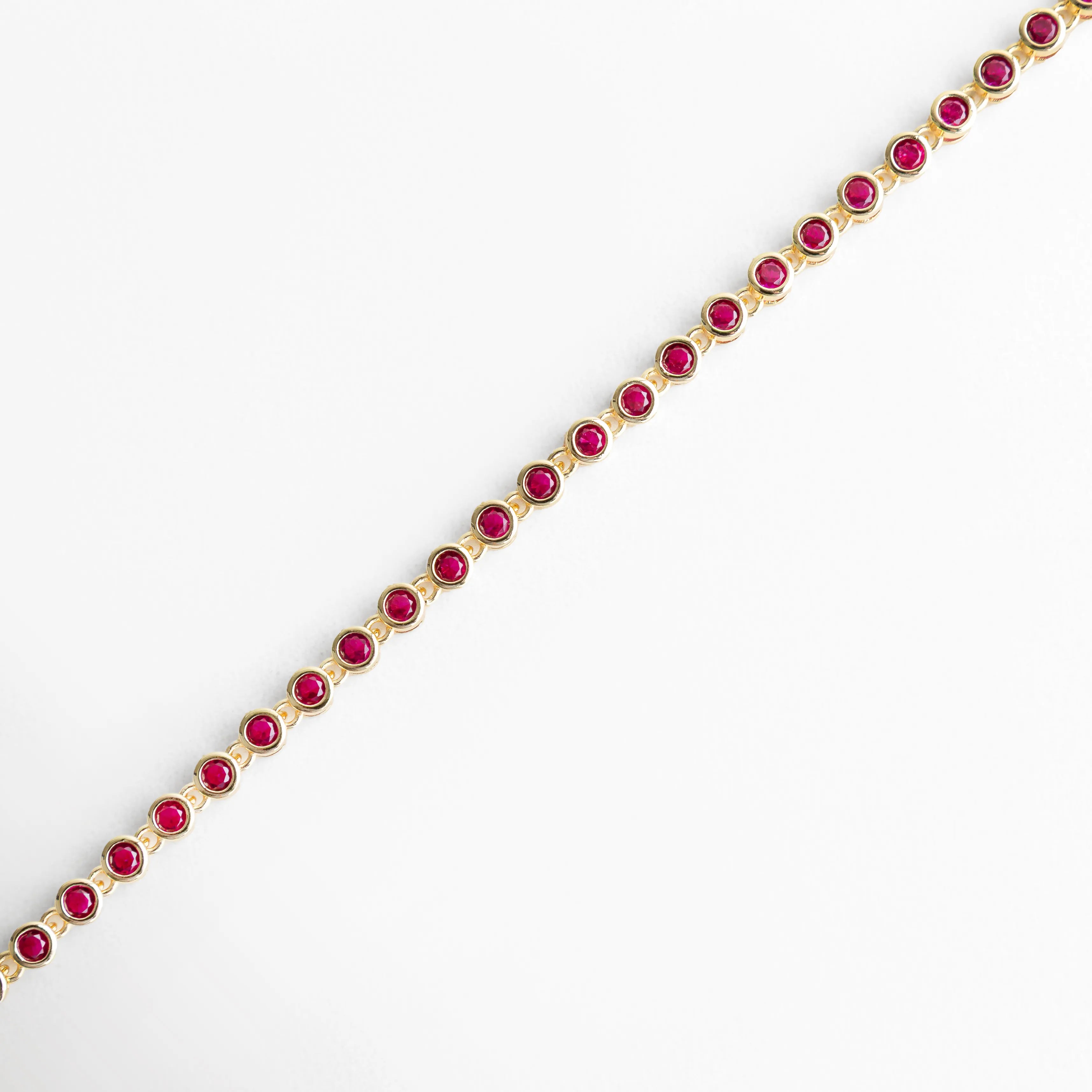 Vista lateral de pulsera dorada con zirconias fucsia en línea continua, Perfil de pulsera con piedras fucsia brillantes y diseño fino, Pulsera vista de lado con estructura delicada y zirconias fucsia, Lateral de pulsera dorada con incrustaciones fucsia elegantes, Detalle lateral con alineación de piedras fucsia brillantes