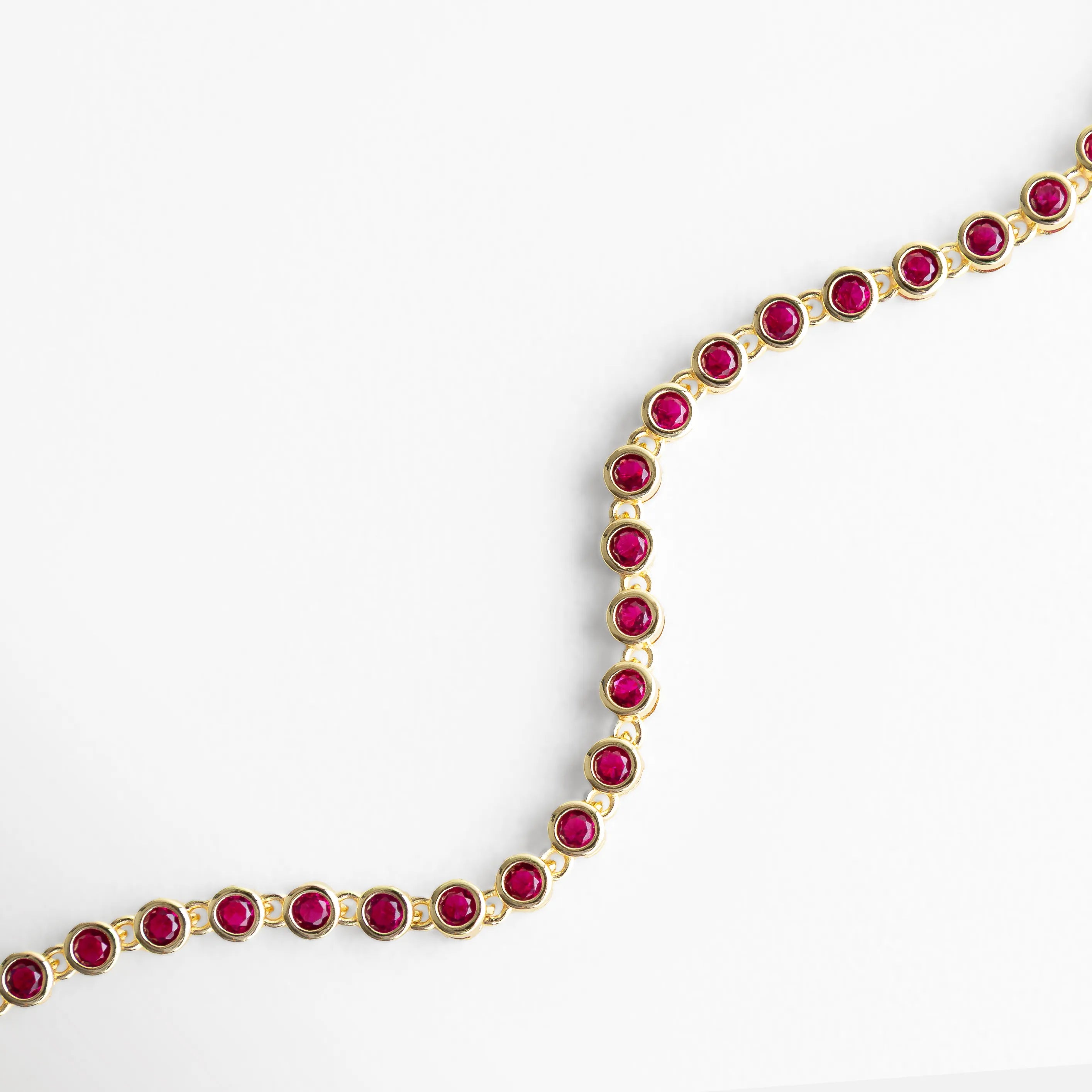 Pulsera dorada con zirconias fucsia en forma curva y diseño delicado, Vista curva de pulsera con piedras fucsia brillantes, Pulsera Rodas fucsia en ángulo curvo con acabado en oro 18K, Curvatura de pulsera con zirconias fucsia y brillo elegante, Pulsera con forma ondulada y piedras fucsia vibrantes
