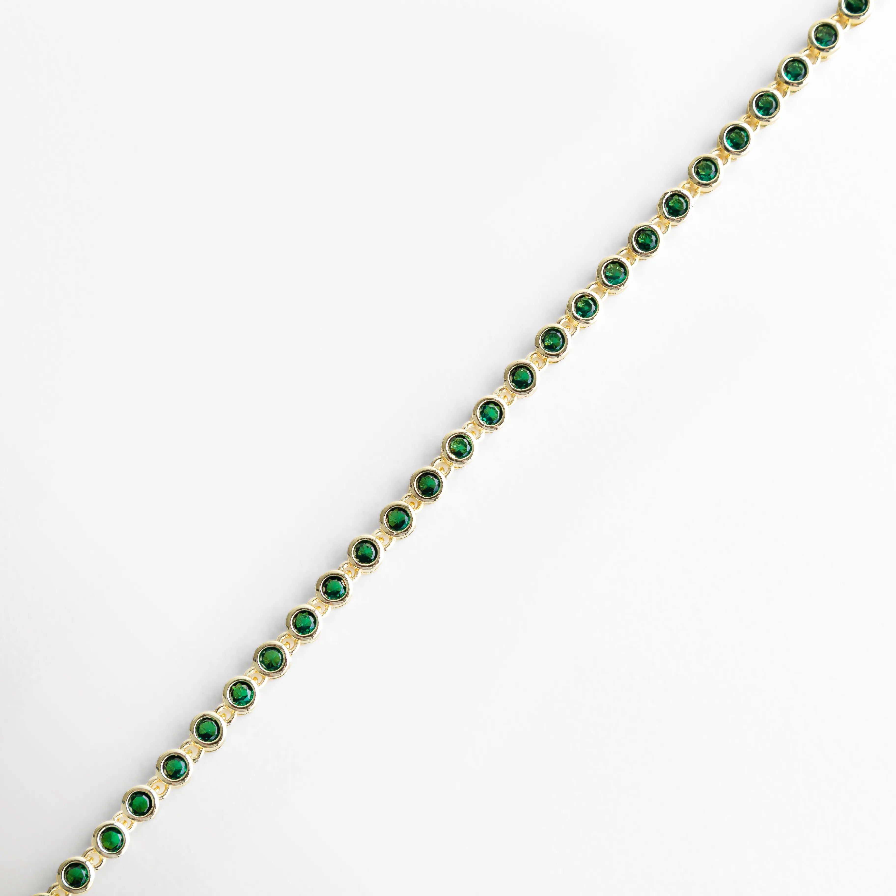 Detalle de pulsera con zirconias cúbicas verdes y acabado dorado brillante, Primer plano de pulsera con piedras verdes y diseño fino, Acercamiento a pulsera dorada con zirconias verdes brillantes, Vista lateral de pulsera con patrón continuo de piedras verdes, Detalle elegante de pulsera con incrustaciones verdes y acabado en oro 18K