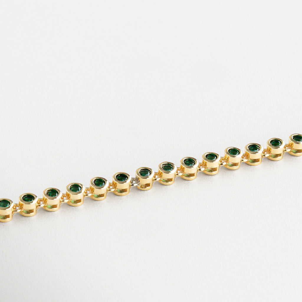 Detalle de zirconias verdes en pulsera dorada, Primer plano de pulsera con incrustaciones verdes, Zirconias cúbicas verdes sobre chapa de oro 18K, Acabado brillante en pulsera con piedras verdes