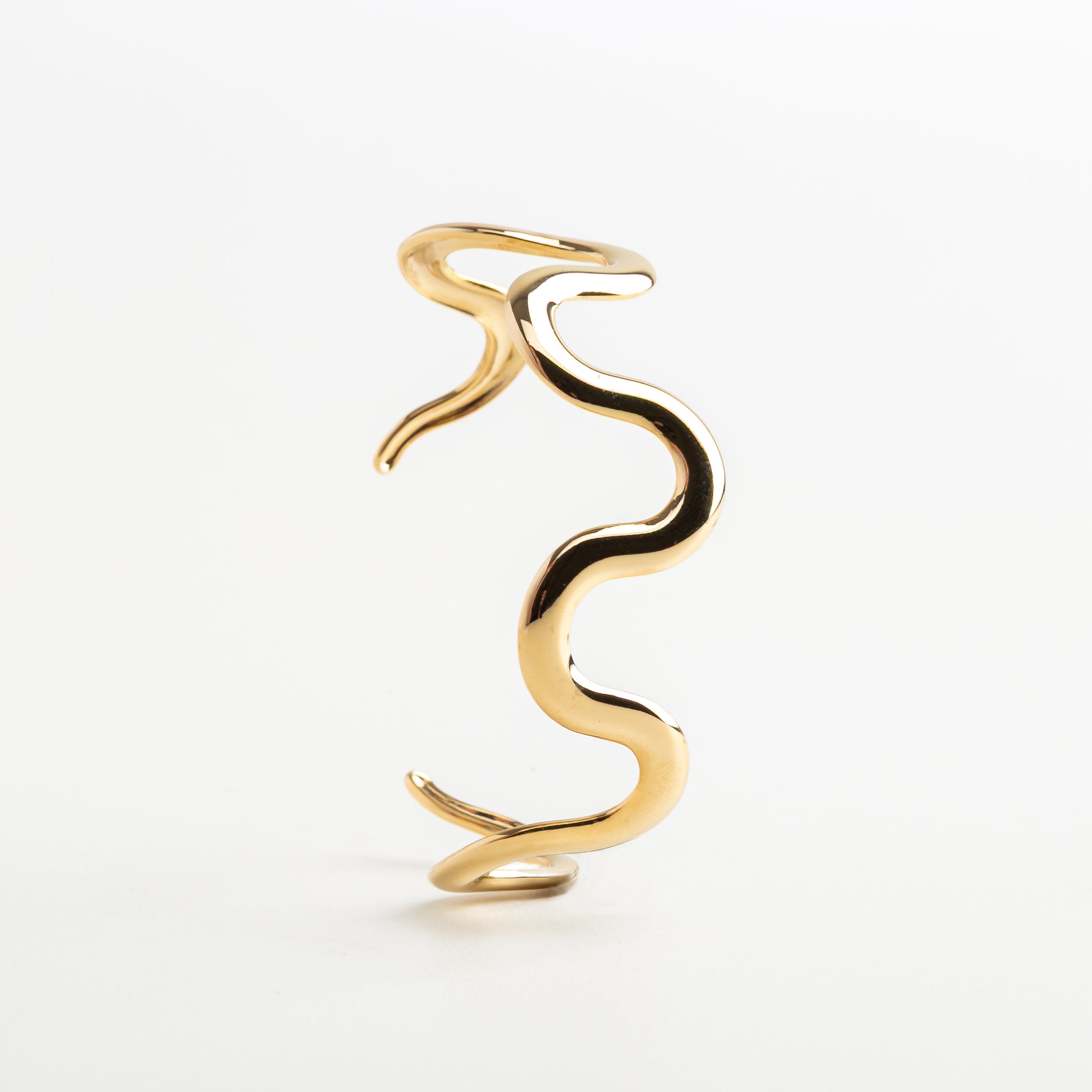 Pulsera tipo brazalete con forma fluida en dorado, Diseño ondulado dorado en acero inoxidable, Pulsera moderna de líneas fluidas y estilo elegante, Detalle del movimiento en pulsera Maya dorada