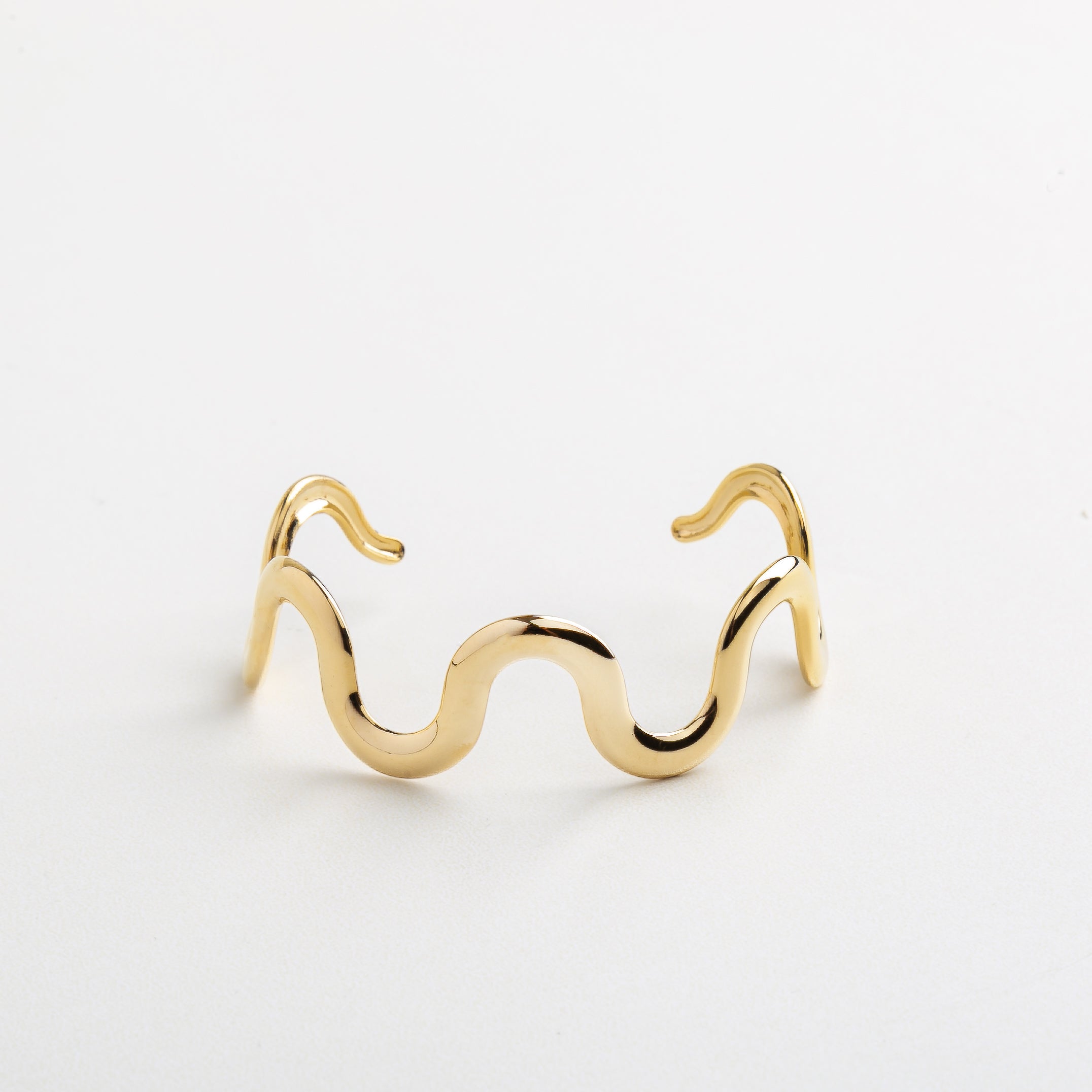 Detalle del diseño ondulado en chapa de oro 18K, Superficie dorada con curvas suaves y brillo sutil, Pulsera con textura fluida y elegante en dorado, Estructura ondulada de acero inoxidable con baño en oro