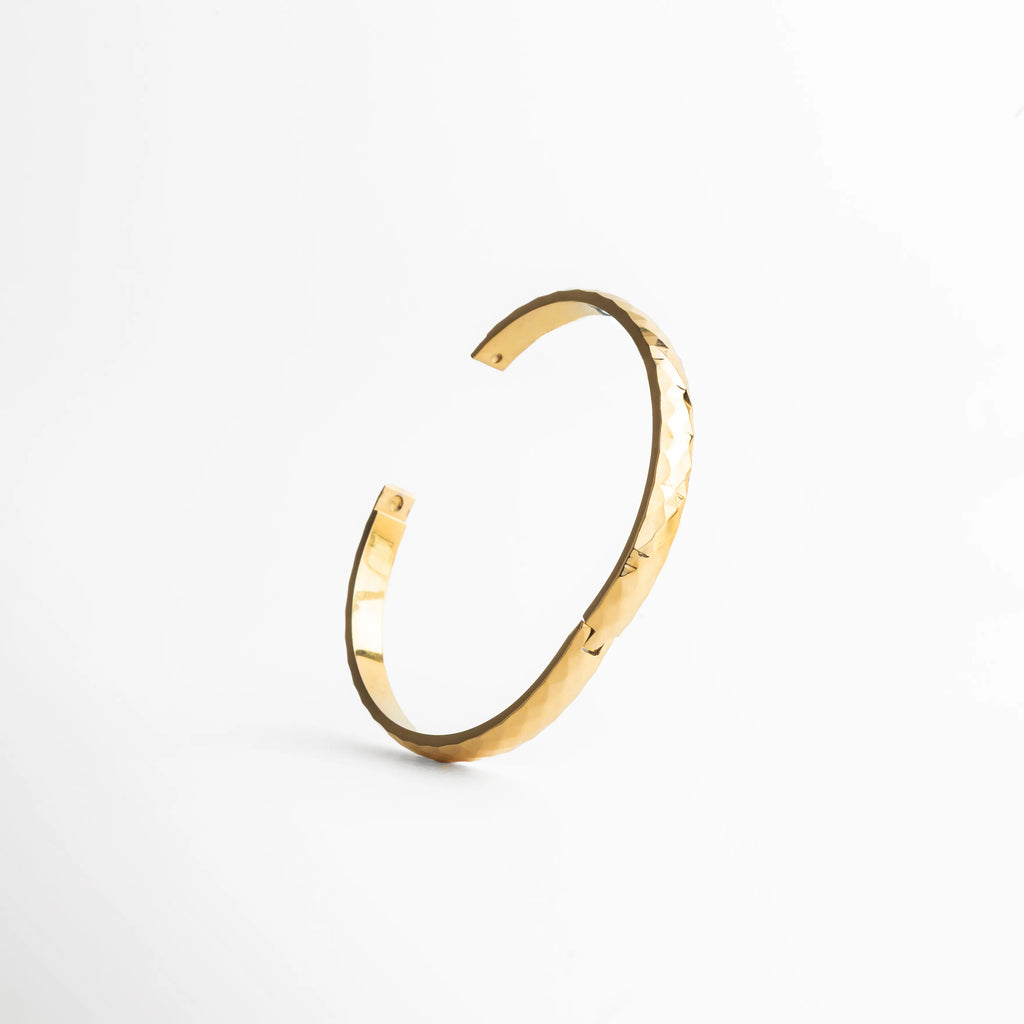 pulsera dorada con textura, acabado facetado joyería, pulsera elegante mujer, joyería dorada sofisticada, pulsera moderna, accesorios minimal, pulsera chic