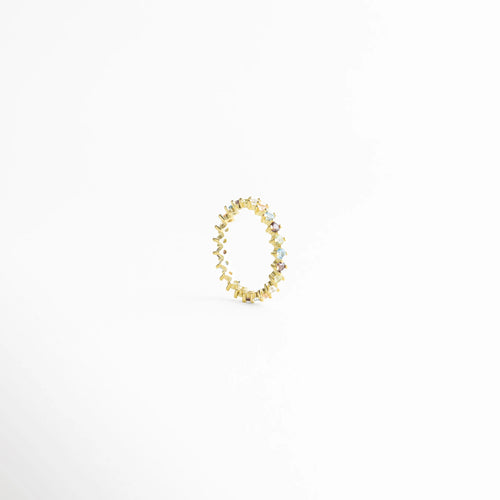 Vista superior del anillo circular de plata dorada resaltando el engaste de las circonias, Anillo de banda completa con piedras preciosas sintéticas de colores en oro 18K, Diseño simétrico de anillo tipo churumbela multicolor con base de plata 925, Anillo artesanal con patrón de circonias brillantes en todo el contorno, Detalle de la circunferencia de anillo dorado con cristales de colores intercalados.