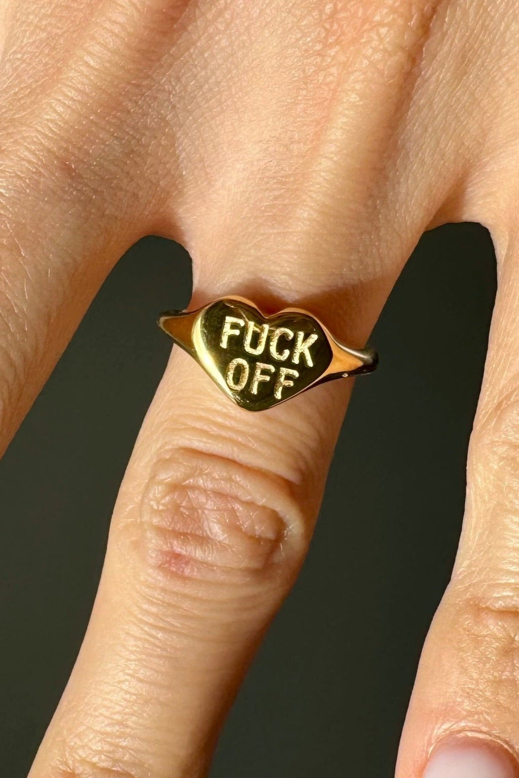 Anillo dorado con grabado Fuck Off usado en dedo con estilo moderno, Anillo minimalista dorado en mano con diseño irreverente, Anillo con mensaje grabado en uso sobre dedo con look casual, Anillo dorado con texto visible combinado con outfit elegante, Anillo de acero inoxidable dorado lucido en mano femenina