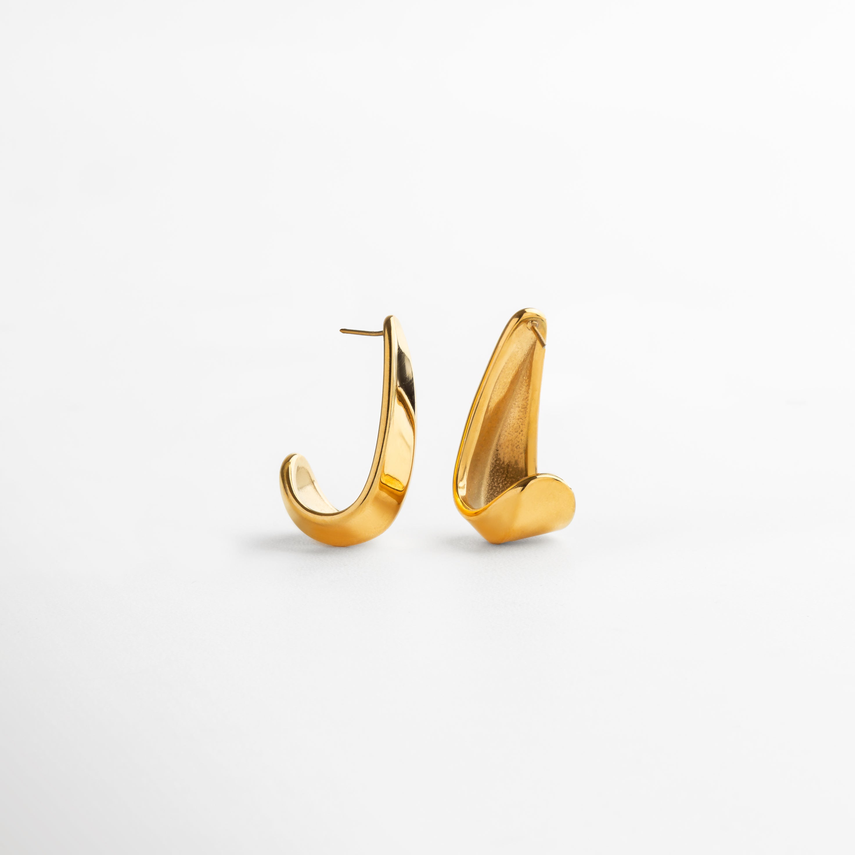 Aretes Mitjana dorados vistos de perfil, con caída recta y diseño ligero que estiliza el rostro. Vista lateral de arete largo en tono dorado, con acabado liso y forma sencilla pero elegante. Perfil de los aretes Mitjana con diseño vertical de 3.5 cm, ideales para looks casuales o formales. Detalle lateral de aretes dorados de acero inoxidable, con estructura delicada y moderna. Aretes largos vistos desde el lado, con silueta refinada y acabado brillante en dorado.
