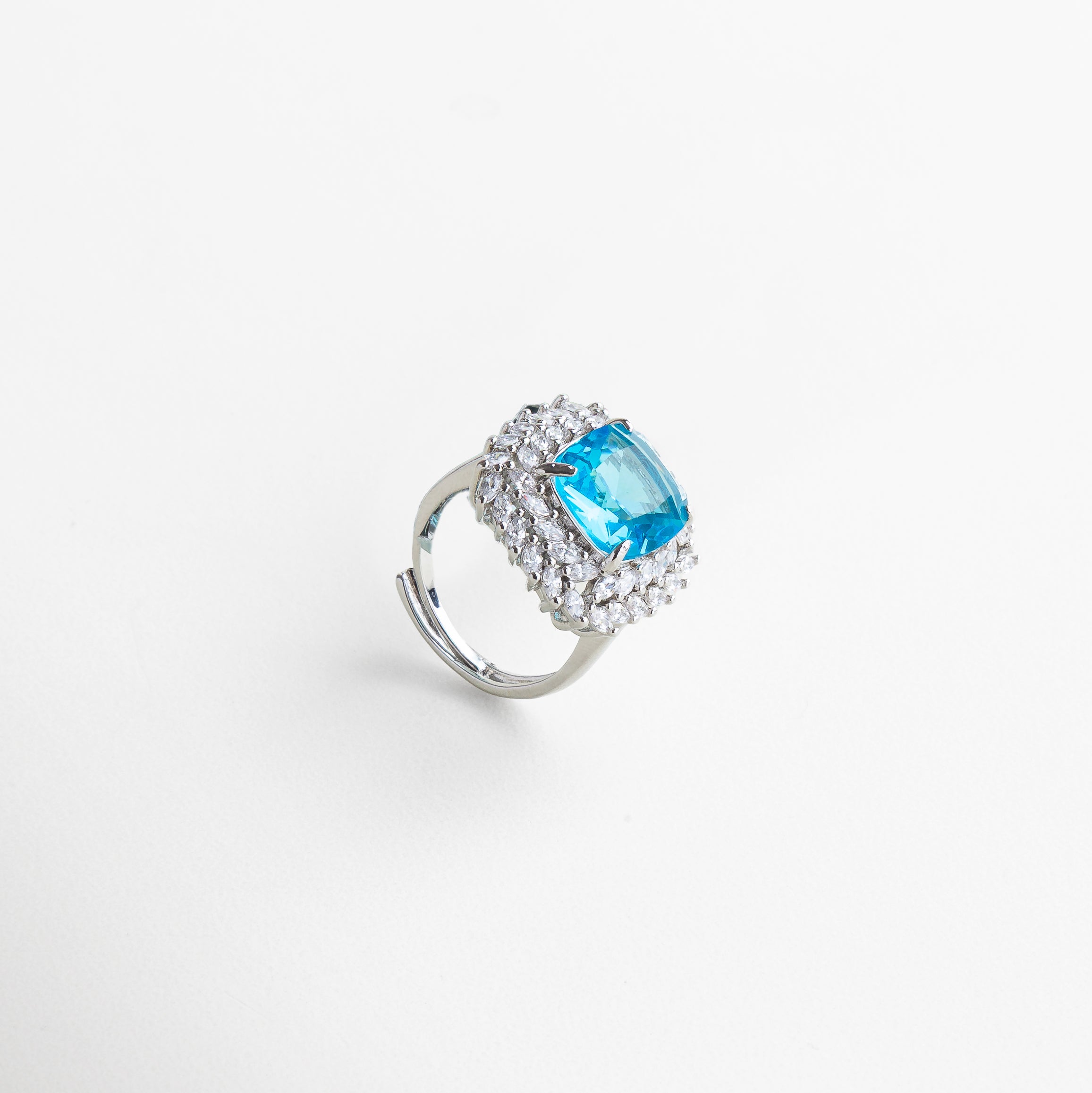 Anillo Lanikai Aqua visto desde el frente, mostrando su centro azul brillante rodeado de bordes plateados. Vista frontal del anillo Lanikai Aqua, con piedra azul claro en forma redonda y acabado elegante en zirconia.
Primer plano del anillo con centro azul, captado desde el frente, resaltando su brillo y diseño sofisticado. Anillo Lanikai Aqua con incrustación de zirconia azul visto desde el frente, evocando la frescura del mar. Frontal del anillo Lanikai Aqua, con piedra azul que refleja la