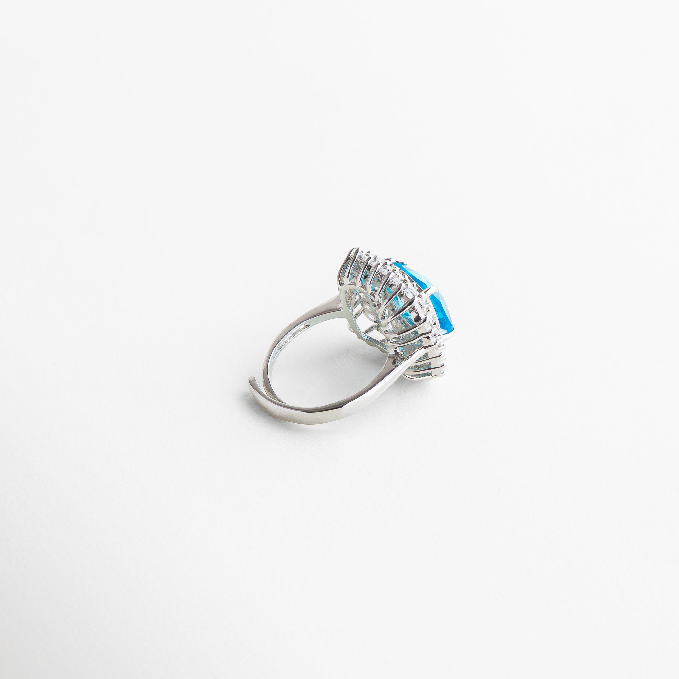 Vista superior del anillo Lanikai Aqua, con piedra central azul de 2 cm rodeada por un marco metálico plateado. Toma cenital del anillo Lanikai Aqua, destacando el contraste entre el azul celeste y el acabado brillante del borde. Anillo Lanikai Aqua visto desde arriba, con incrustación de zirconia azul claro en forma circular. Perspectiva superior del anillo con piedra azul, captando su diseño elegante y moderno. Vista desde arriba del anillo Lanikai Aqua, con efecto luminoso en el centro az