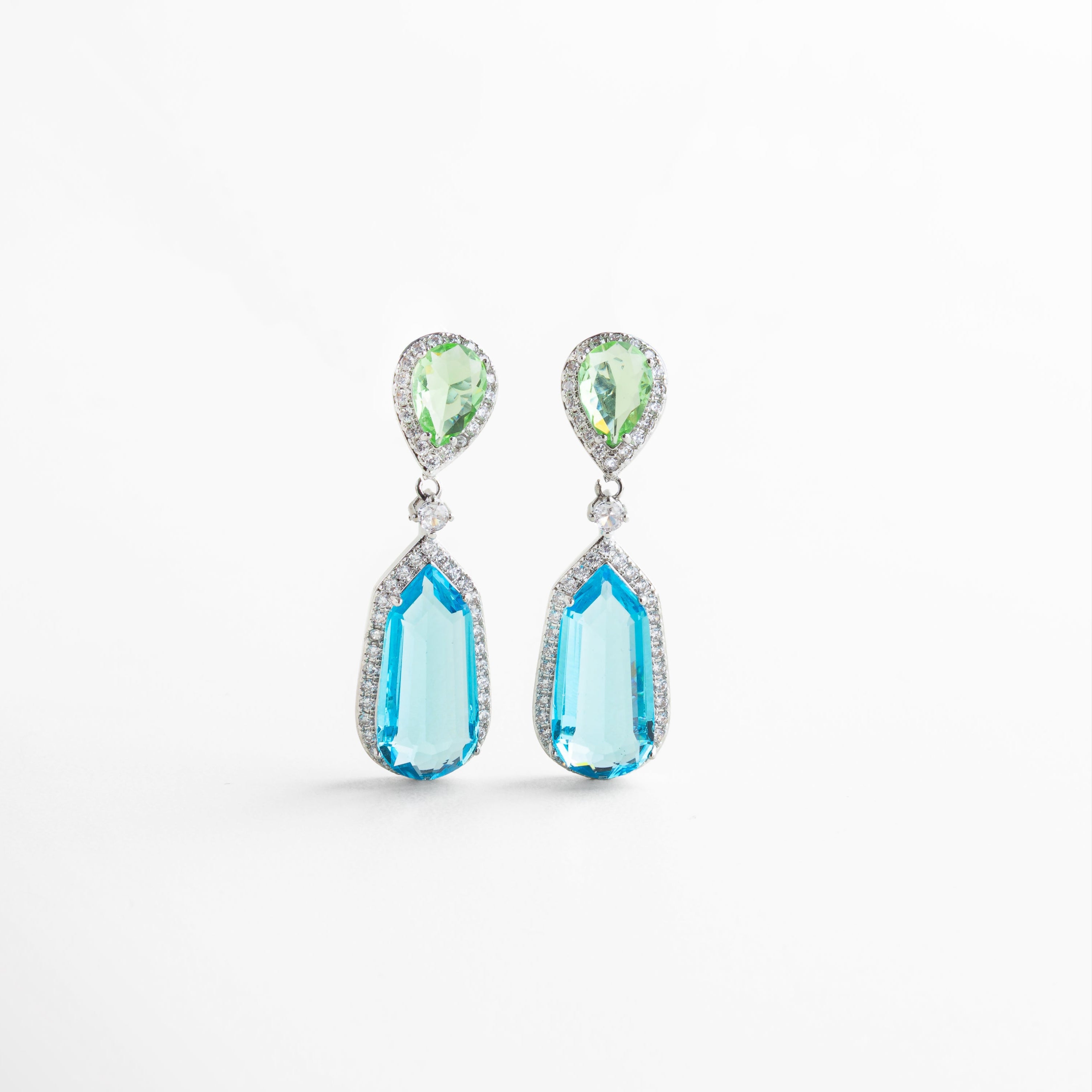 Detalle de diamantes de laboratorio en peridoto y topacio azul sobre base de plata, Primer plano de aretes con acabado pulido y piedras brillantes de laboratorio, Close-up de incrustaciones coloridas sobre Plata 925, Textura y color de piedras verdes y azules en aretes elegantes 