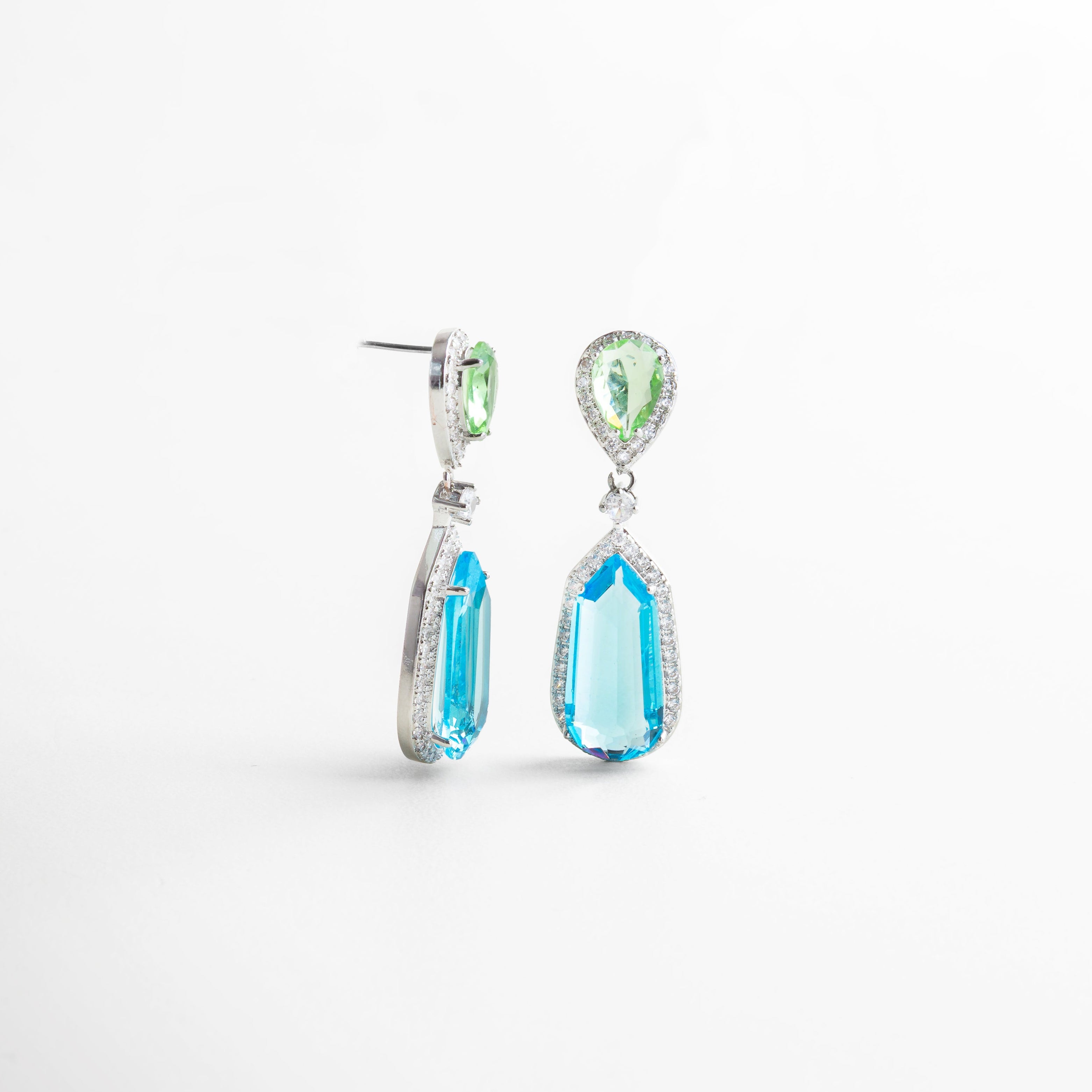 Aretes colgantes de plata vistos en ángulo con diseño estilizado, Pendientes largos con caída delicada en peridoto y azul topacio, Aretes con doble piedra vistos en perspectiva, ideales para eventos especiales, Diseño moderno y sofisticado de perfil en plata con colores vibrantes