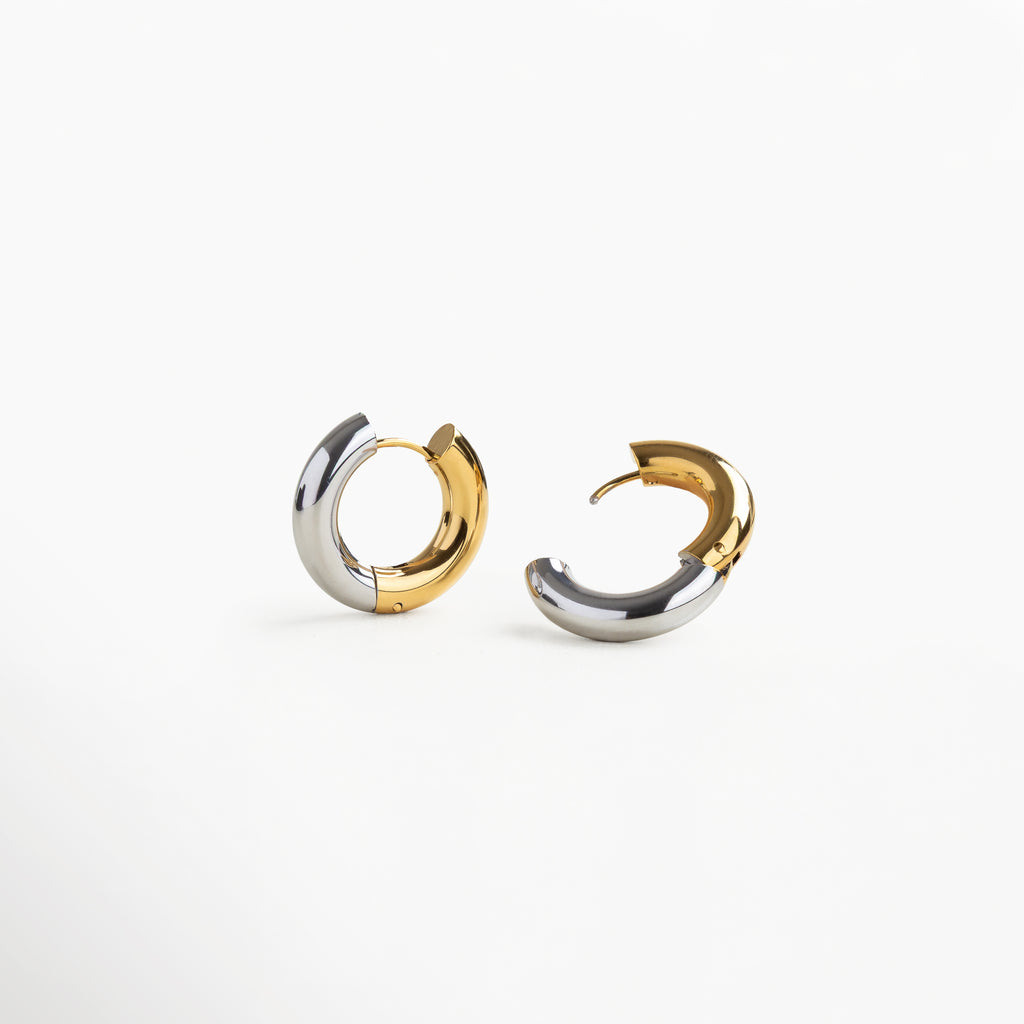Detalle lateral de arracadas en dorado y plateado, Arracadas bicolor con acabado brillante de acero, Aretes chunky bitono vistos en ángulo, Pendientes bitono con acabado metálico dual, Vista en detalle de arracadas de acero inoxidable bitono