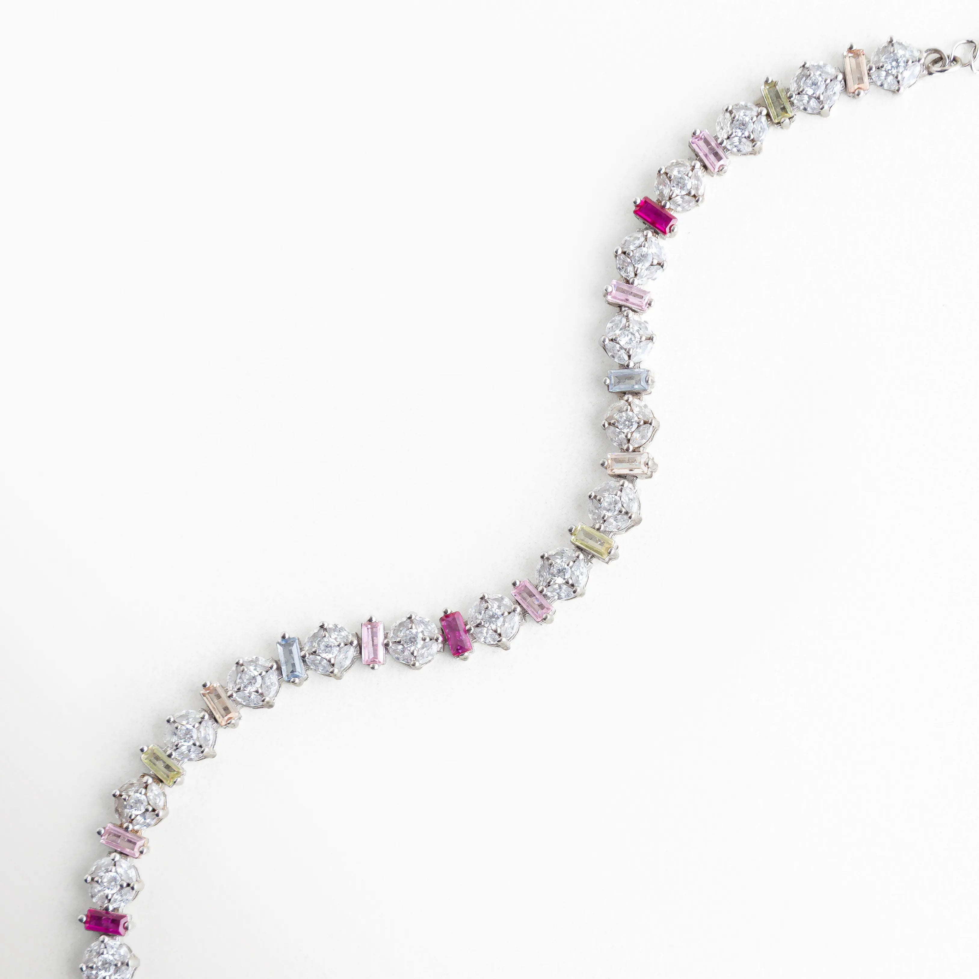 Pulsera flexible de plata 925 con diseño de piedras multicolor en forma de S, Brazalete plateado con circonias de colores mostrando su caída y movimiento natural, Pulsera de oro blanco y plata con cristales brillantes dispuestos en hilera curva, Diseño de joyería artesanal: pulsera "Rainbow" plateada con piedras de diferentes formas, Pulsera delgada de plata con destellos multicolores, ideal para un look juvenil y elegante.