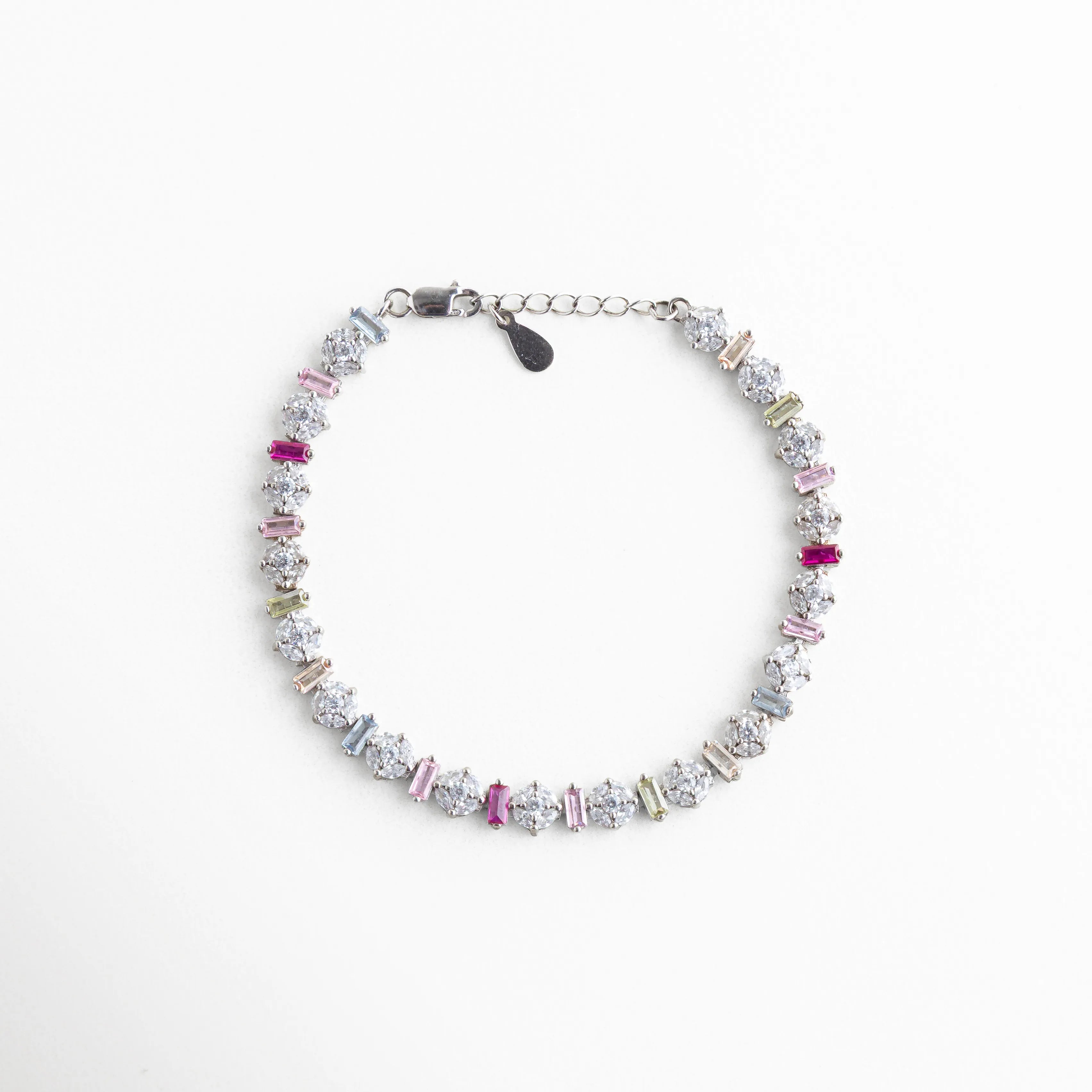 Vista cenital de pulsera circular de plata con baño de oro blanco y circonias, Brazalete completo de plata 925 con patrón infinito de piedras de colores brillantes, Pulsera tipo eternidad plateada con circonias multicolor, vista de producto completa, Accesorio de muñeca en plata de ley con acabado de lujo y piedras de colores, Composición circular de pulsera plateada con incrustaciones de cristal tipo diamante y color.