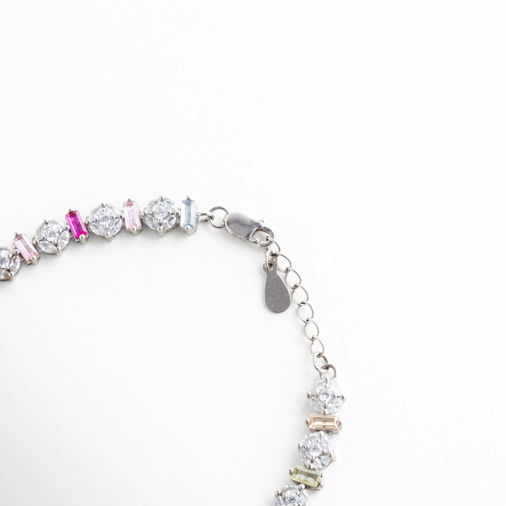Detalle del broche de langosta y cadena de extensión en pulsera de plata 925, Vista técnica del cierre seguro y acabado en oro blanco de pulsera multicolor, Broche ajustable de joyería en plata con placa de autenticidad "925", Detalle de la cadena ajustable para diferentes medidas de muñeca en pulsera dorada blanca, Mecanismo de cierre de pulsera de circonias resaltando la calidad del metal.