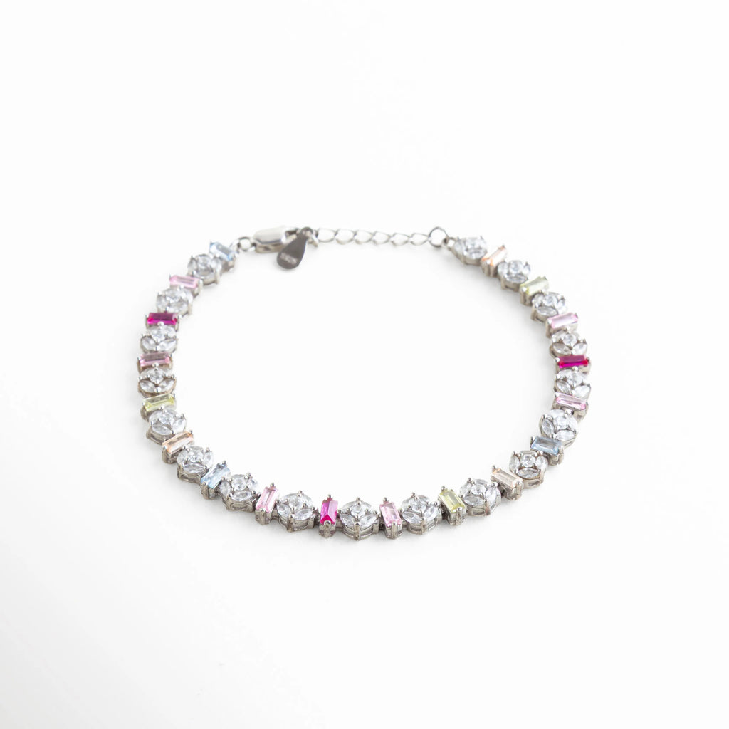 Perspectiva angular de pulsera de plata resaltando el brillo de las circonias bajo la luz, Pulsera de lujo accesible en oro blanco con piedras de colores, vista de 45 grados, Brazalete brillante de plata ley 925 con diseño "Pastel Rainbow", Joyería de tendencia: pulsera delgada plateada con circonias de corte baguette y redondo, Vista lateral de pulsera multicolor mostrando el relieve y brillo de los cristales.
