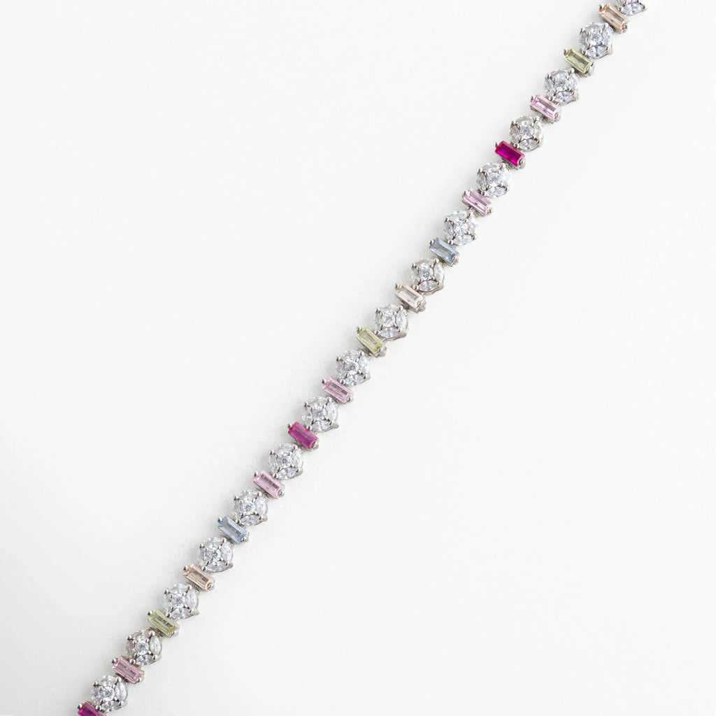 Pulsera de Plata 925 con baño de oro blanco y circonias de colores en cortes redondos y rectangulares, Detalle de pulsera tipo "tennis" multicolor con incrustaciones de circonia premium, Primer plano de brazalete plateado con piedras brillantes en tonos rosa, azul y amarillo, Joyería fina: pulsera de plata de ley con cristales de colores y acabado en oro blanco, Vista detallada de los engastes de circonia en pulsera plateada de diseño contemporáneo.