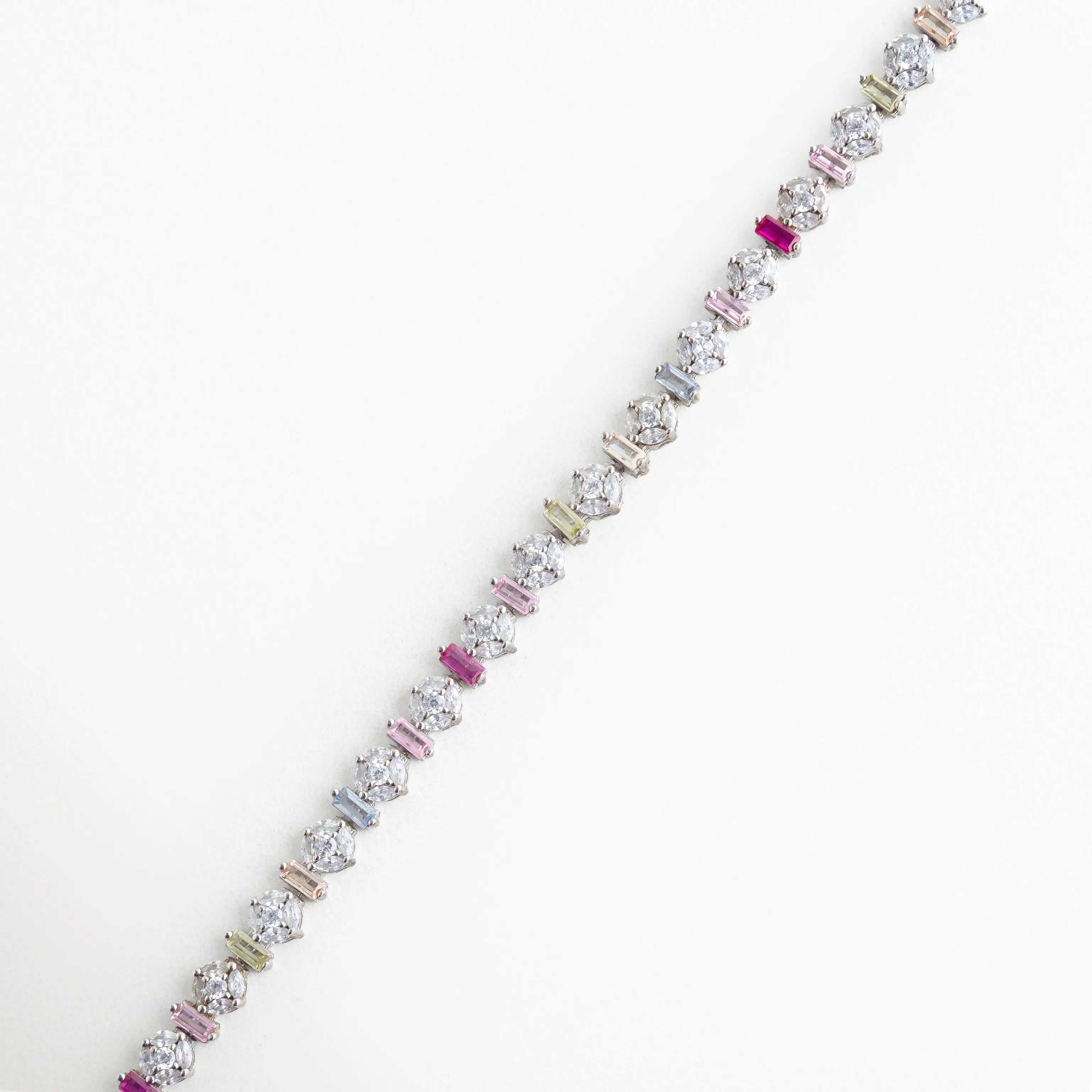 Pulsera de Plata 925 con baño de oro blanco y circonias de colores en cortes redondos y rectangulares, Detalle de pulsera tipo "tennis" multicolor con incrustaciones de circonia premium, Primer plano de brazalete plateado con piedras brillantes en tonos rosa, azul y amarillo, Joyería fina: pulsera de plata de ley con cristales de colores y acabado en oro blanco, Vista detallada de los engastes de circonia en pulsera plateada de diseño contemporáneo.