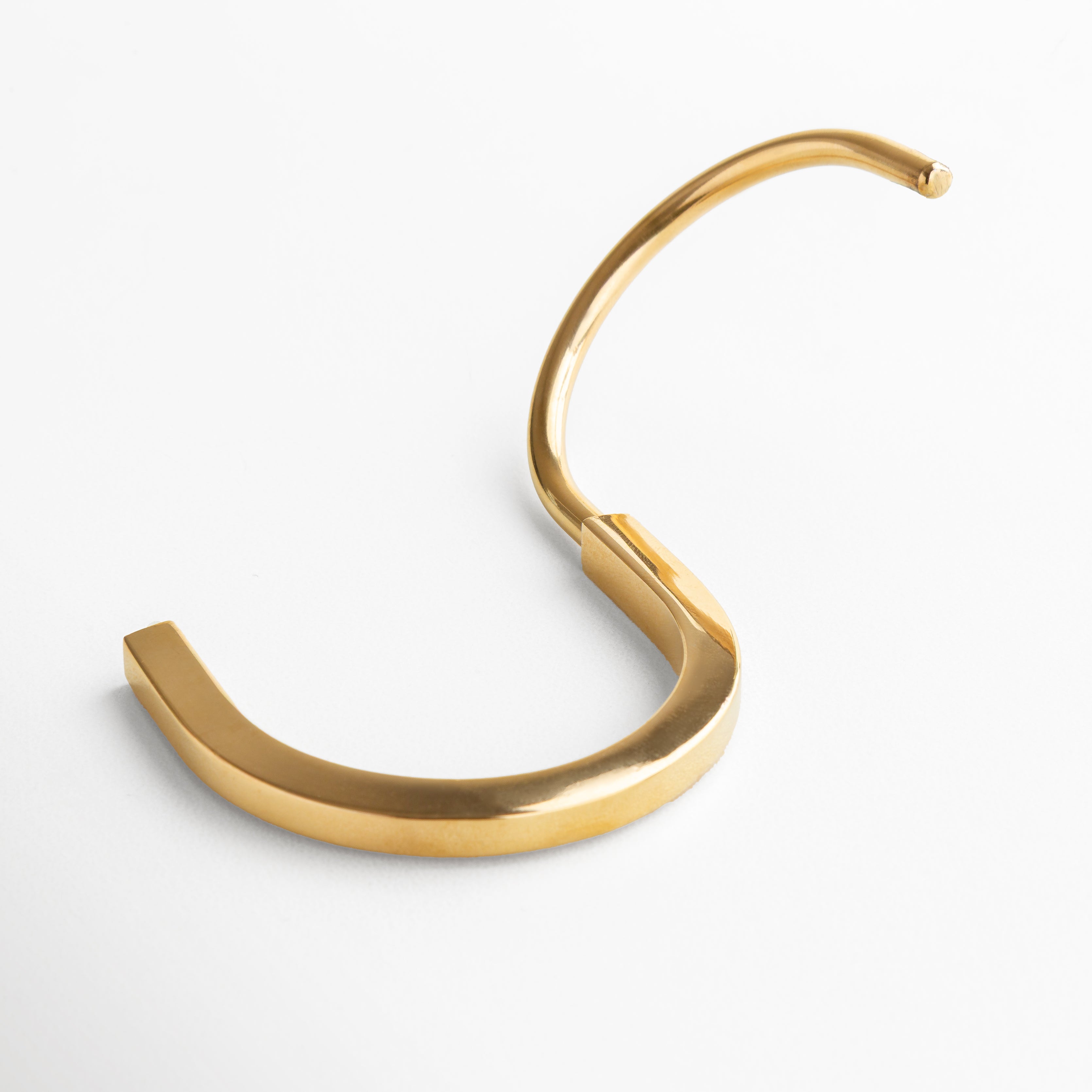 Pulsera rígida dorada con diseño estructurado y líneas limpias, Acabado en chapa de oro 18K que aporta un brillo cálido y sofisticado., Diseño envolvente que resalta la fuerza y el estilo moderno., Medidas de 7.3 cm de longitud y 5.8 cm de ancho, ideal para un ajuste cómodo, Perfecta para destacar como pieza statement en cualquier outfit contemporáneo.