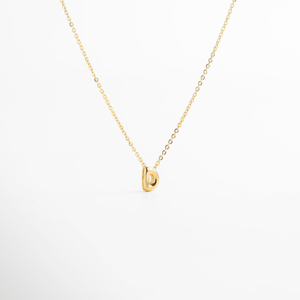 grosor del collar mini con inicial D dorada, detalle del diseño bold en la letra D del collar, cadena fina con dije de inicial D, acabado enchapado en oro 18K con letra D, collar de cobre con recubrimiento dorado