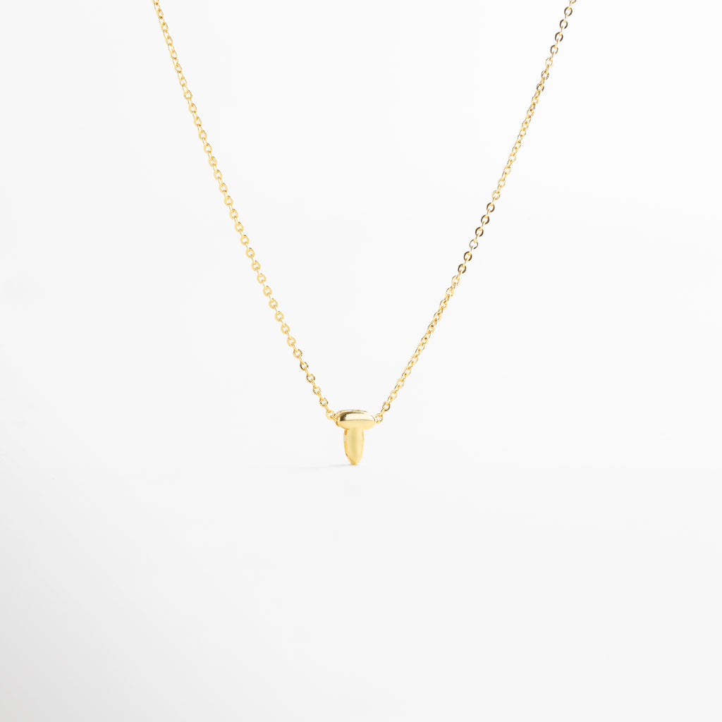 detalle de letra inicial T mini bold en collar dorado, textura del dije con inicial T chapada en oro, collar con inicial T vista de cerca, acabado brillante del collar con letra T, forma de la letra T en diseño mini bold
