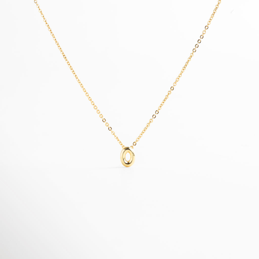 detalle de letra inicial O mini bold en collar dorado, textura del dije con inicial O chapada en oro, collar con inicial O vista de cerca, acabado brillante del collar con letra O, forma de la letra O en diseño mini bold