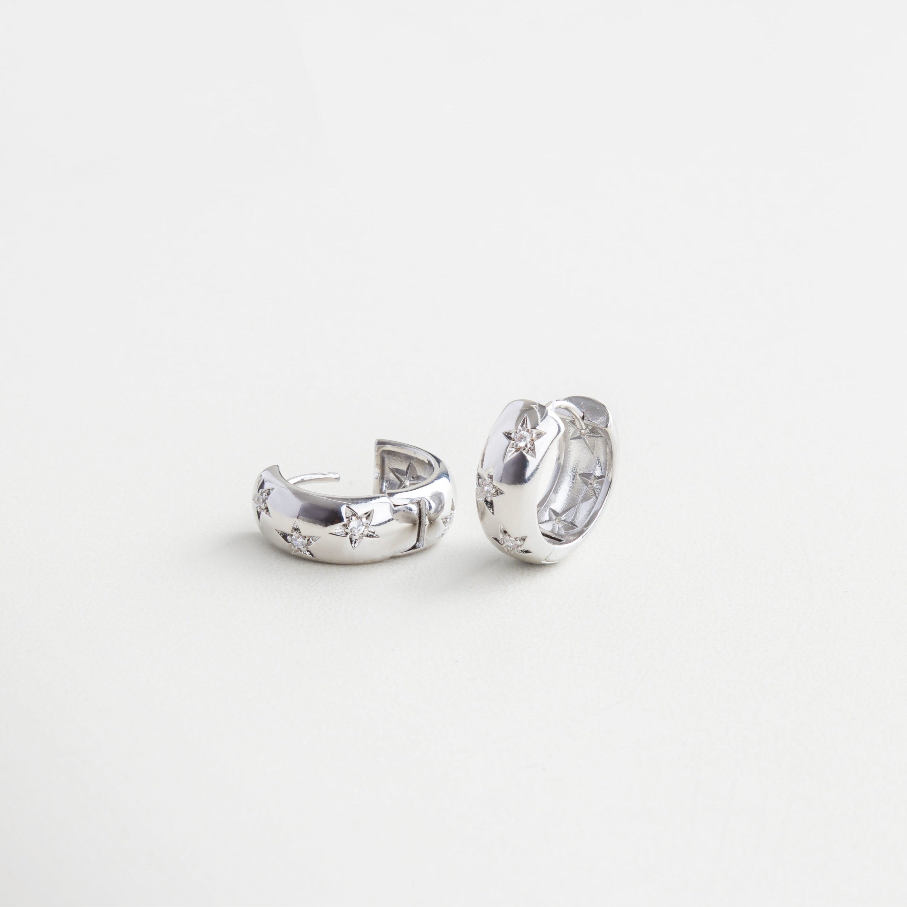 Cierre tipo broche discreto en aro plateado, Mecanismo de clip oculto y seguro, Detalle de broche integrado al diseño, Sistema de cierre funcional y estético, Cierre metálico con acabado en oro blanco