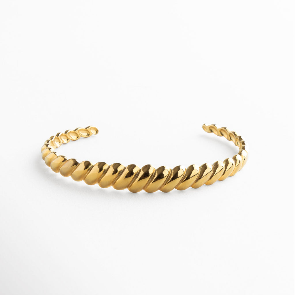 Pulsera rígida dorada con textura de líneas diagonales, Brazalete dorado de acero inoxidable con diseño geométrico, Pulsera dorada tipo cuff con patrón grabado en diagonal, Joya dorada minimalista con acabado texturizado