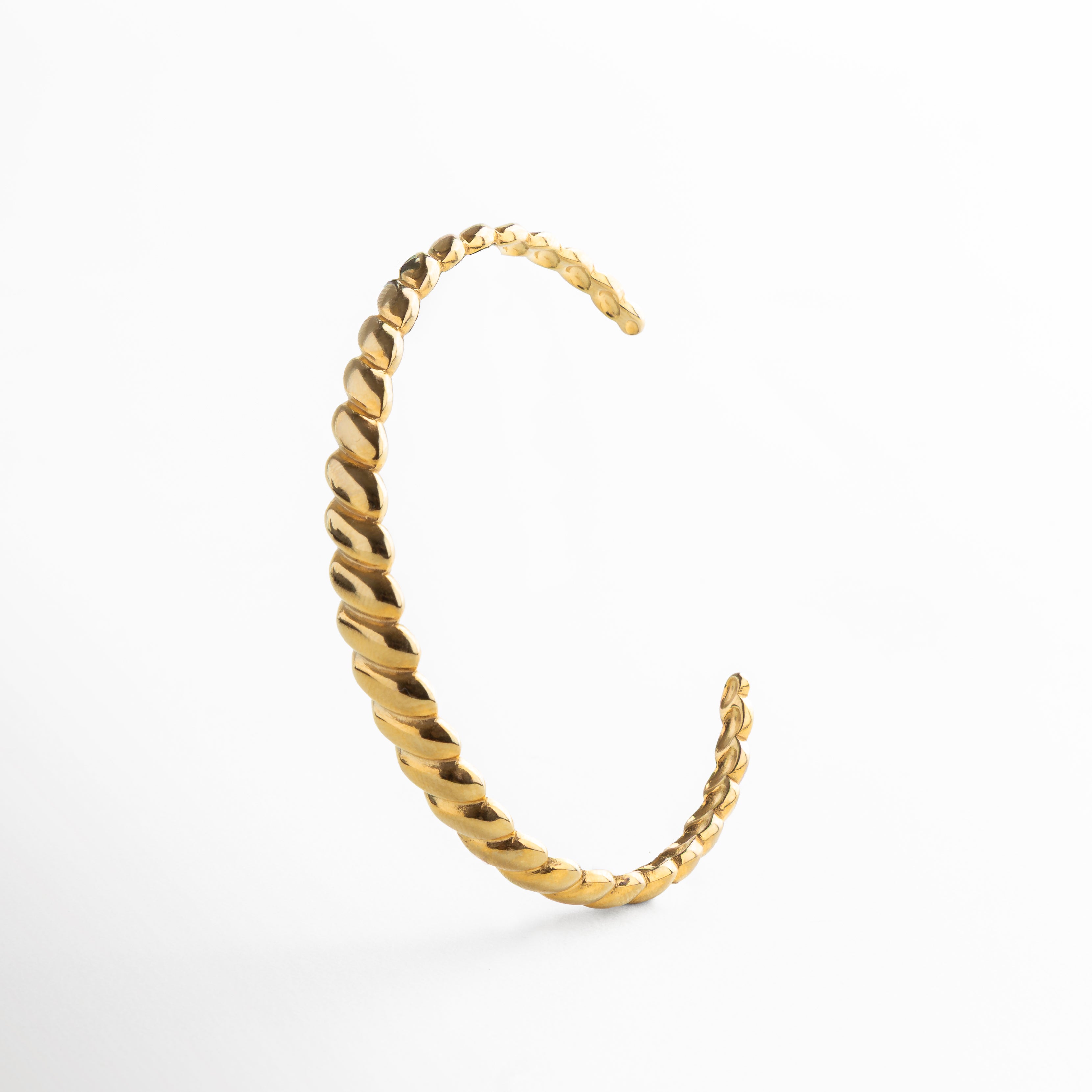 Detalle de las líneas diagonales grabadas en pulsera dorada, Textura geométrica sobre superficie dorada pulida, Primer plano del grabado moderno en dorado, Acabado dorado con patrón visual dinámico