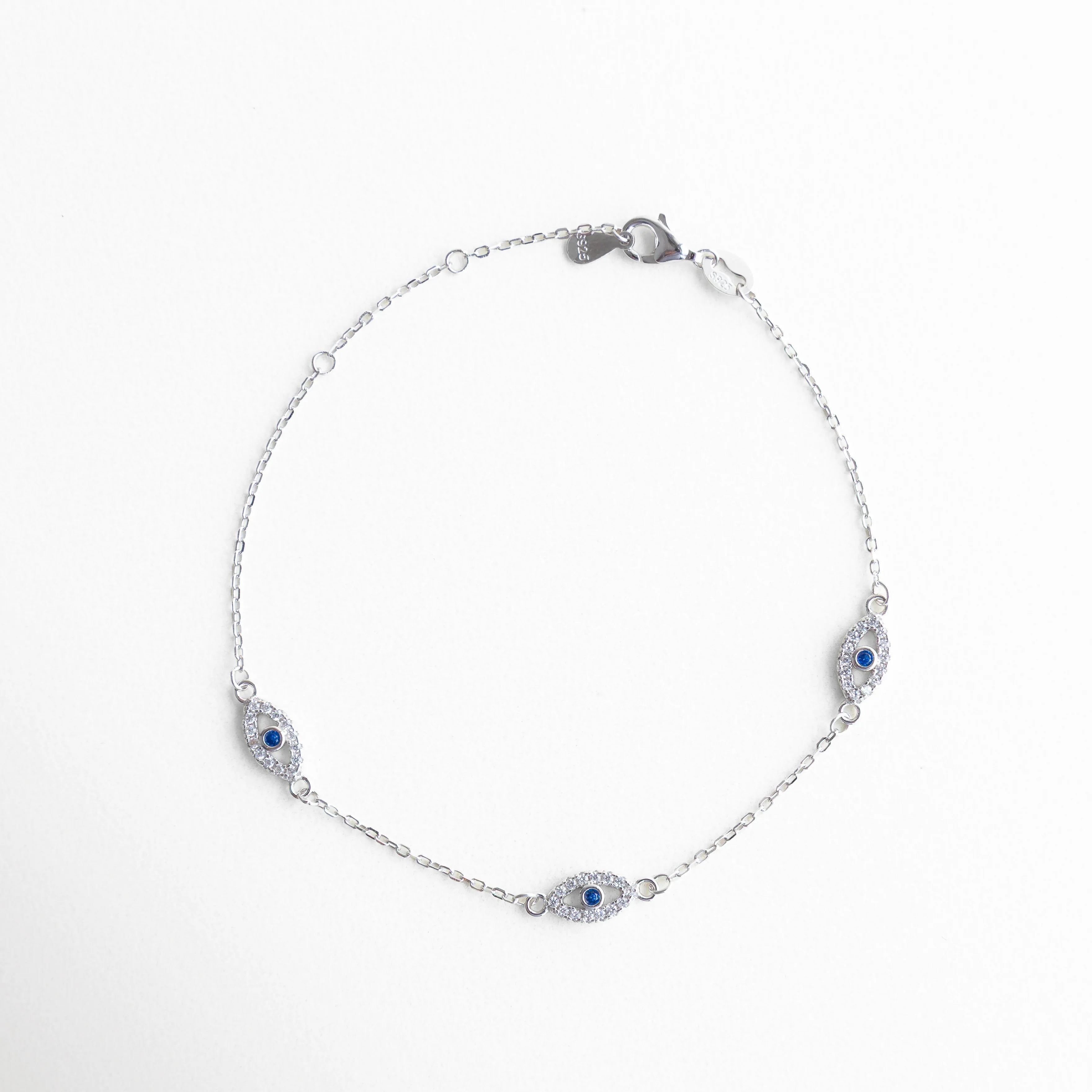 Pulsera completa plata 925 con tres ojos turcos en forma circular elegante, Vista cerrada de pulsera con zirconias y amuletos ojo turco azul, Pulsera delicada con tres dijes protectores en acabado oro blanco, Pulsera femenina con diseño equilibrado y piedras brillantes, Joyería fina tipo pulsera con ojos turcos y zirconias en todo el contorno