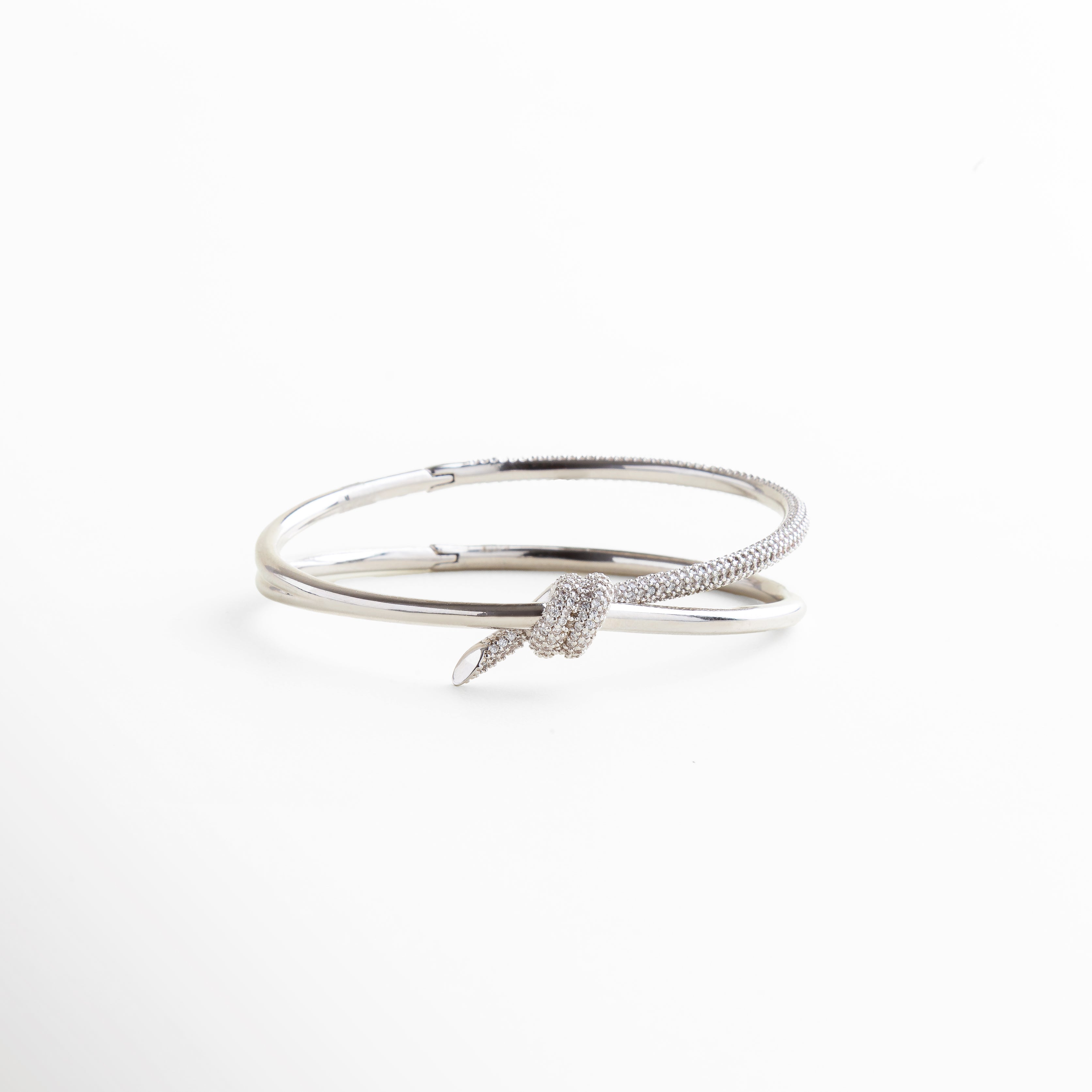 escala real de pulsera rígida plateada con nudo, proporción del nudo central en relación con la pulsera, tamaño visible en muñeca con diseño abierto, dimensión visual del brazalete en uso, forma estructurada y tamaño del diseño rígido
