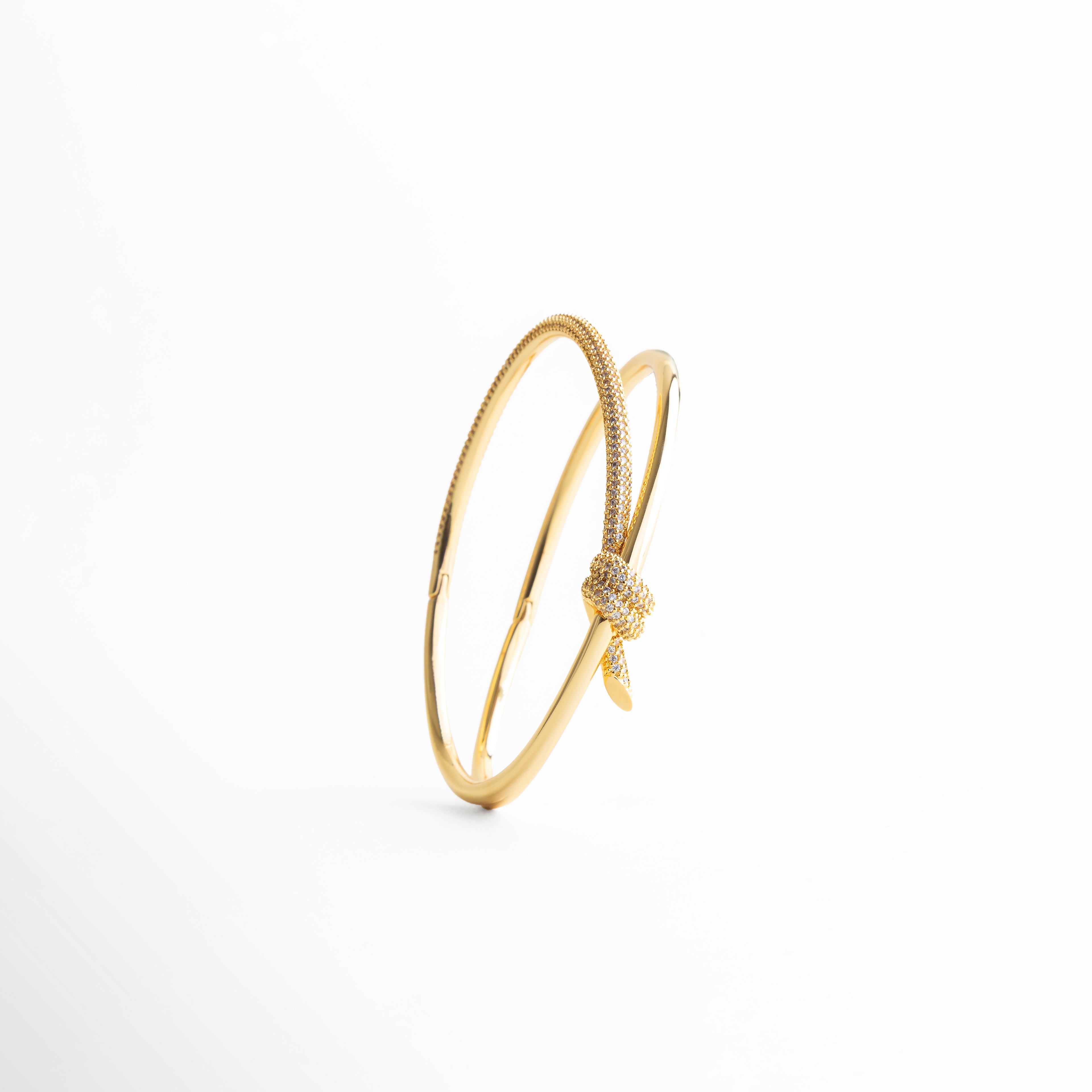 pulsera dorada vista lateral, detalle nudo pulsera, joyería dorada moderna, pulsera fina mujer, accesorios sofisticados chic, pulsera minimal elegante, joyería femenina contemporánea, pulsera refinada