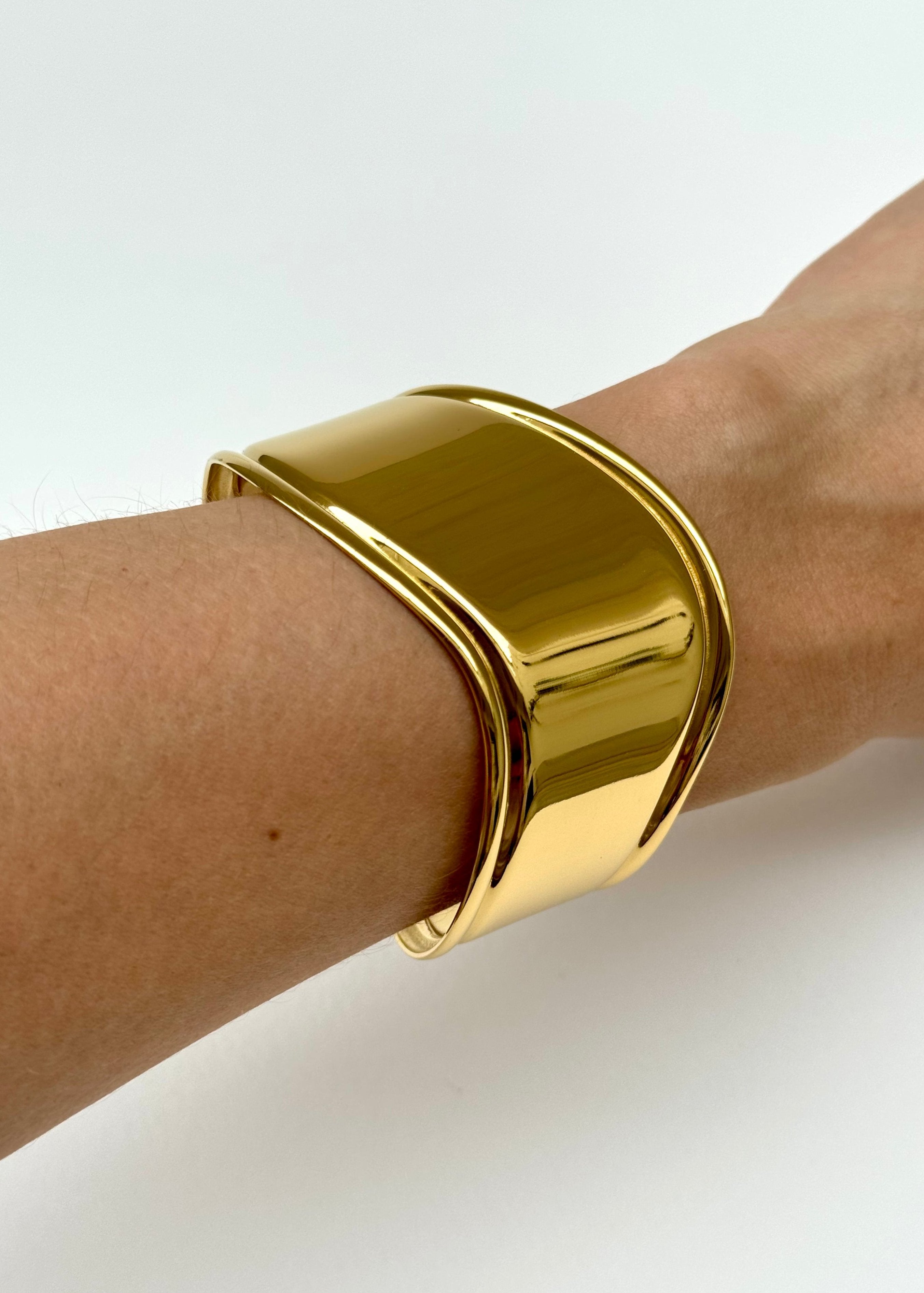 pulsera dorada en uso, pulsera cuff outfit, joyería femenina en uso, accesorios dorados chic, pulsera statement en muñeca, joyería moderna mujer