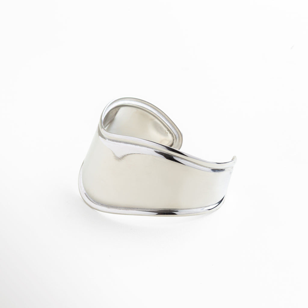 Acercamiento al brillo intenso del acabado plateado, Pulido espejo que refleja la luz de forma uniforme, Estructura sólida y continua del brazalete, Grosor consistente en todo el contorno, Línea curva elegante en diseño minimalista