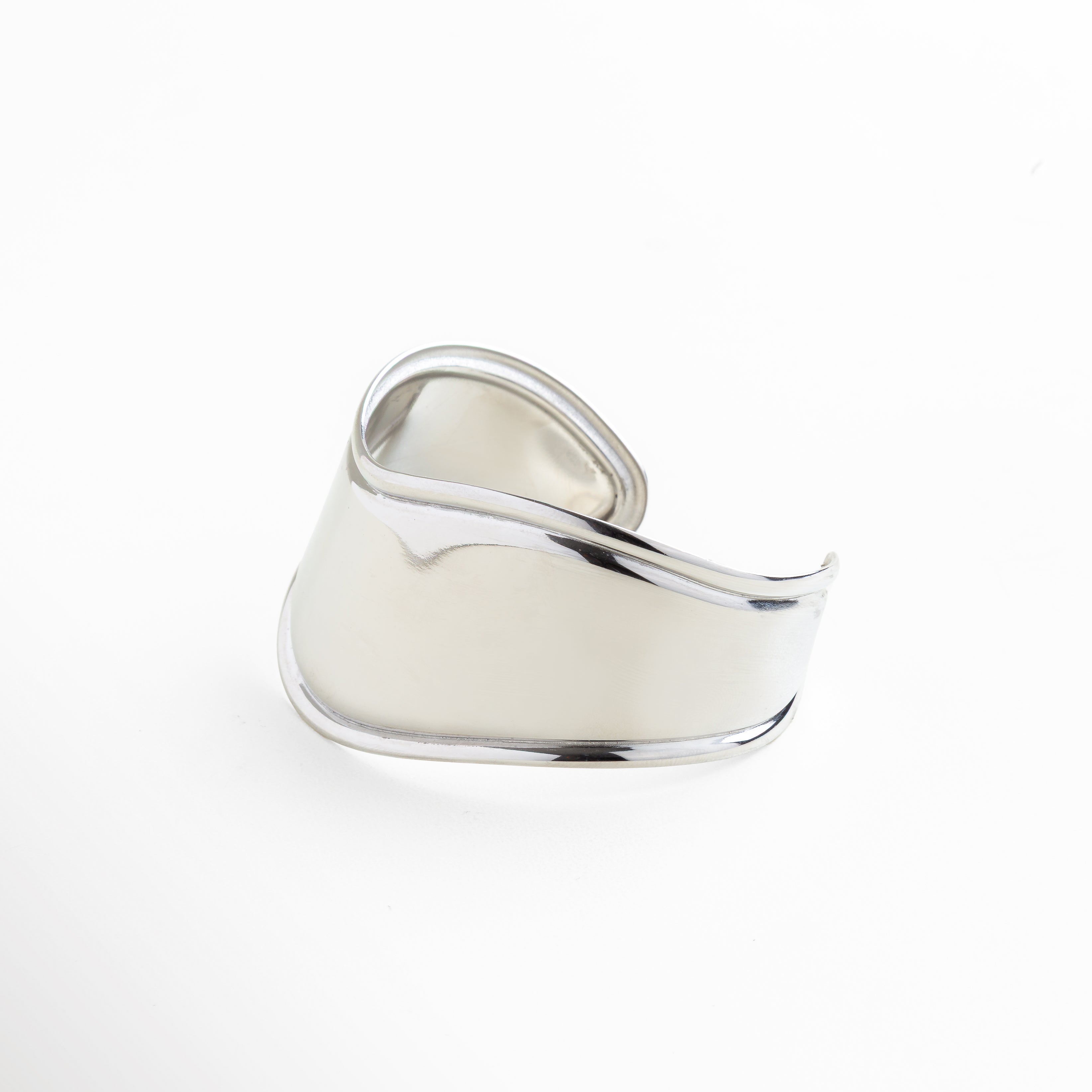 Acercamiento al brillo intenso del acabado plateado, Pulido espejo que refleja la luz de forma uniforme, Estructura sólida y continua del brazalete, Grosor consistente en todo el contorno, Línea curva elegante en diseño minimalista