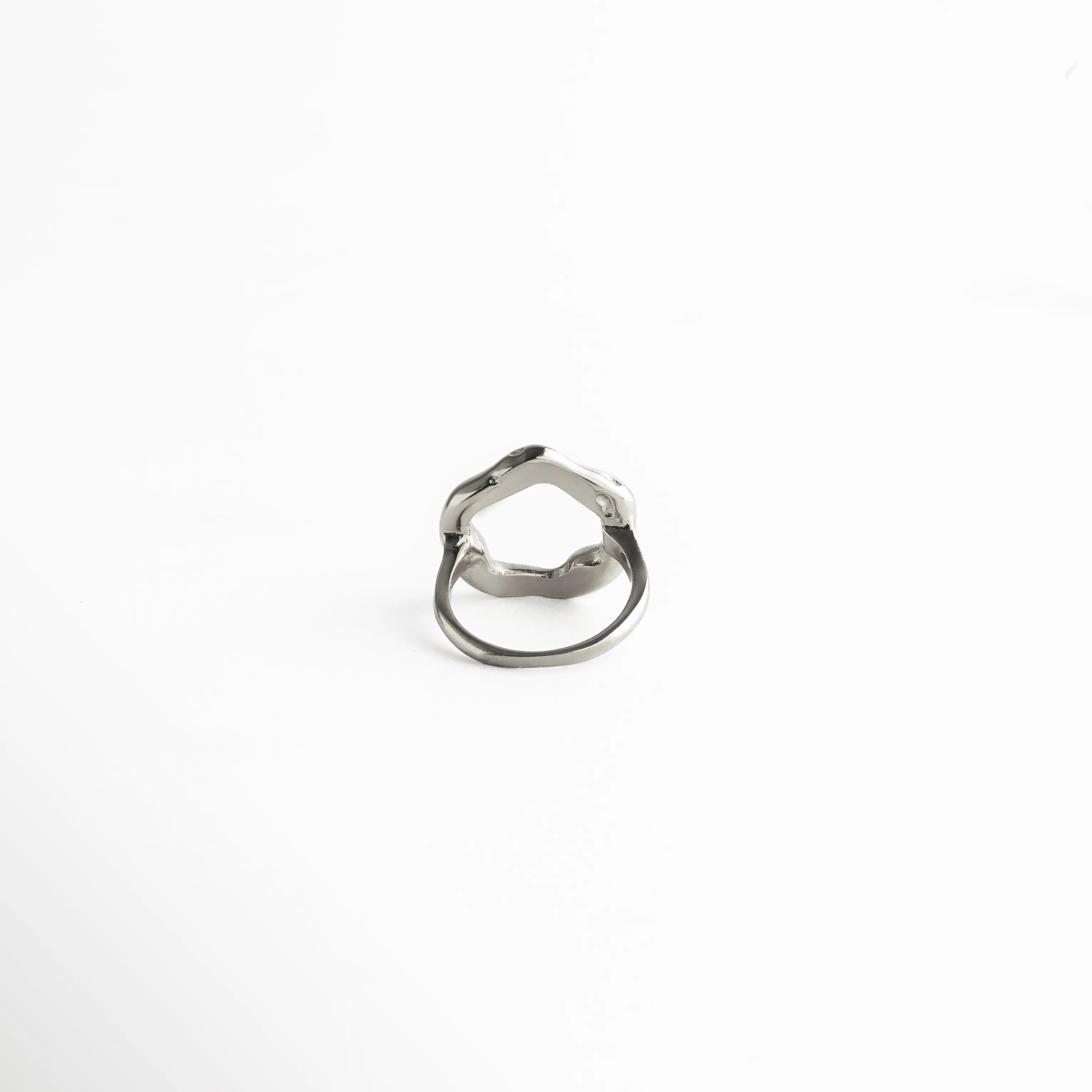 Diseño abierto en la parte superior con acabado metálico pulido, ideal para complementar looks sofisticados con un toque artístico.