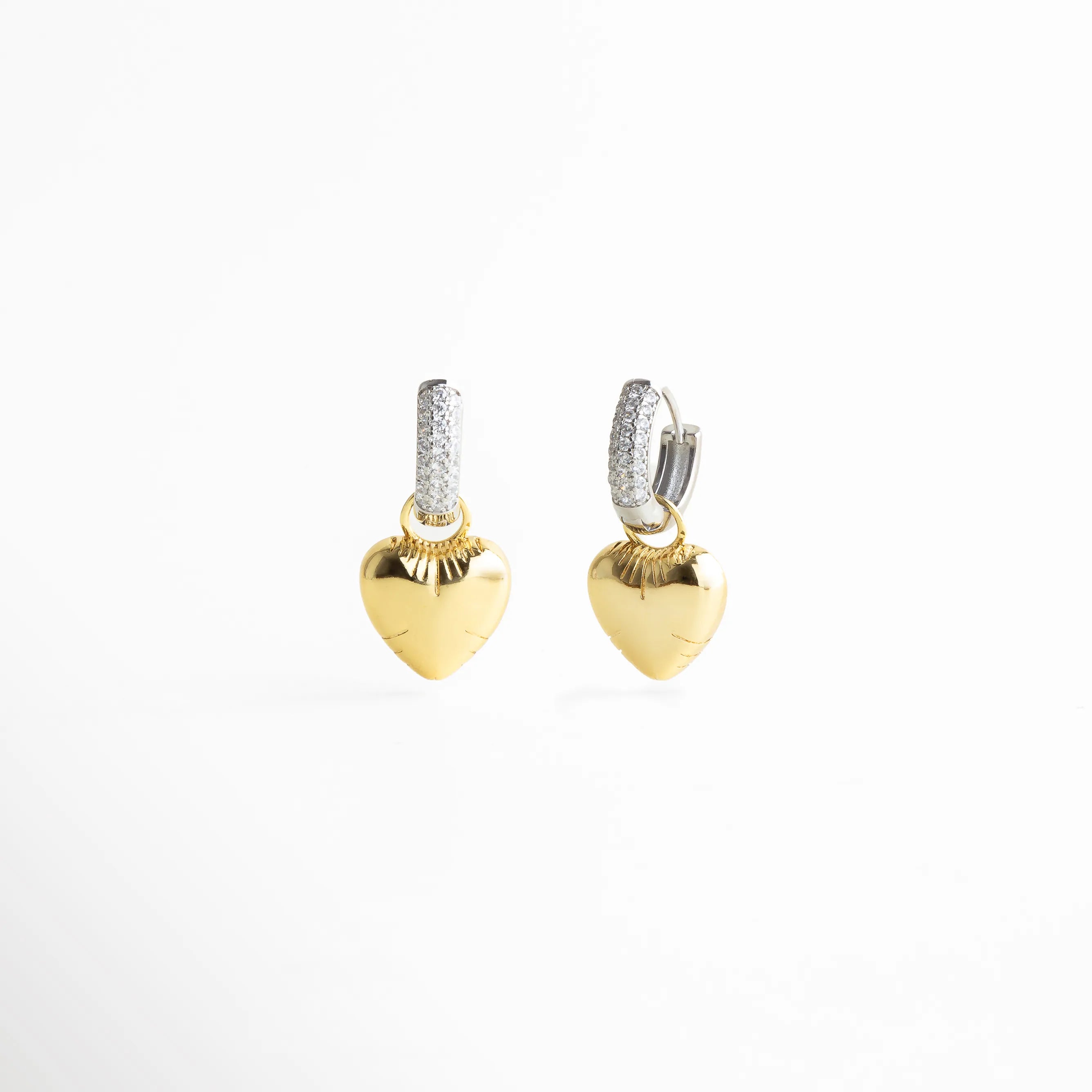 Aretes dorados tipo argolla con dije de corazón pulido, aro plateado con incrustaciones de zirconias y acabado brillante que aporta un toque romántico y moderno.