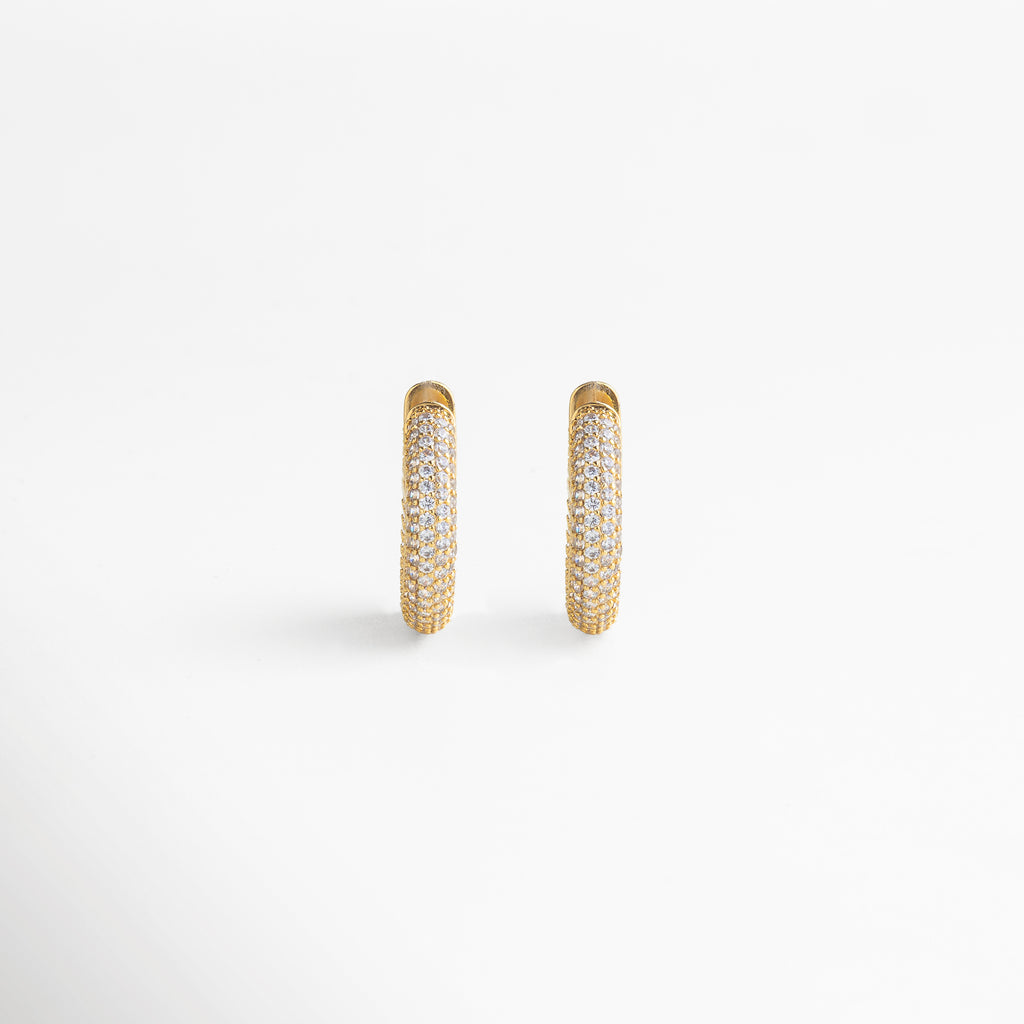 enfoque en la zirconia cúbica, corte preciso y brillo intenso, engaste cuidado que resalta cada gema, acabado dorado pulido, detalle refinado y elegante